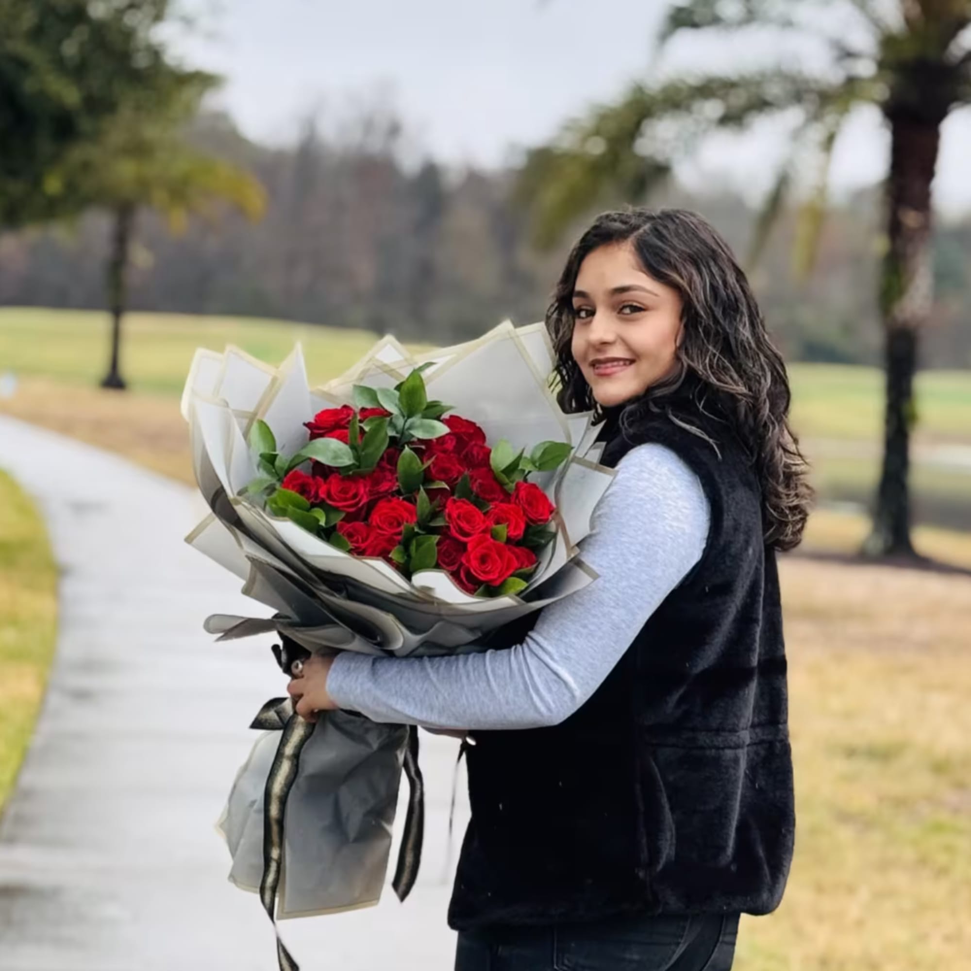 Woman holding a bouquet of red roses wrapped in gray paper