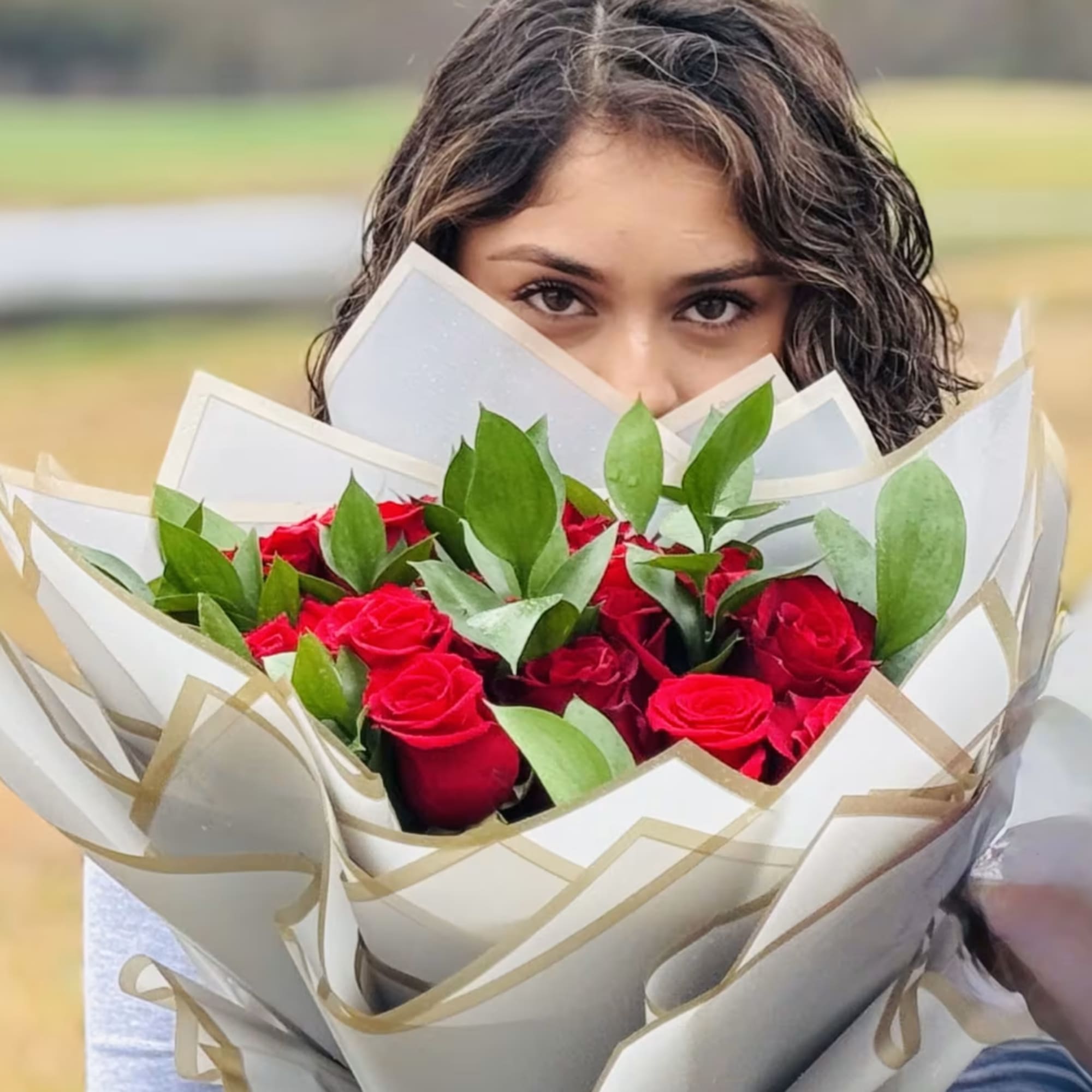 Bouquet of red roses wrapped in white paper with gold trim