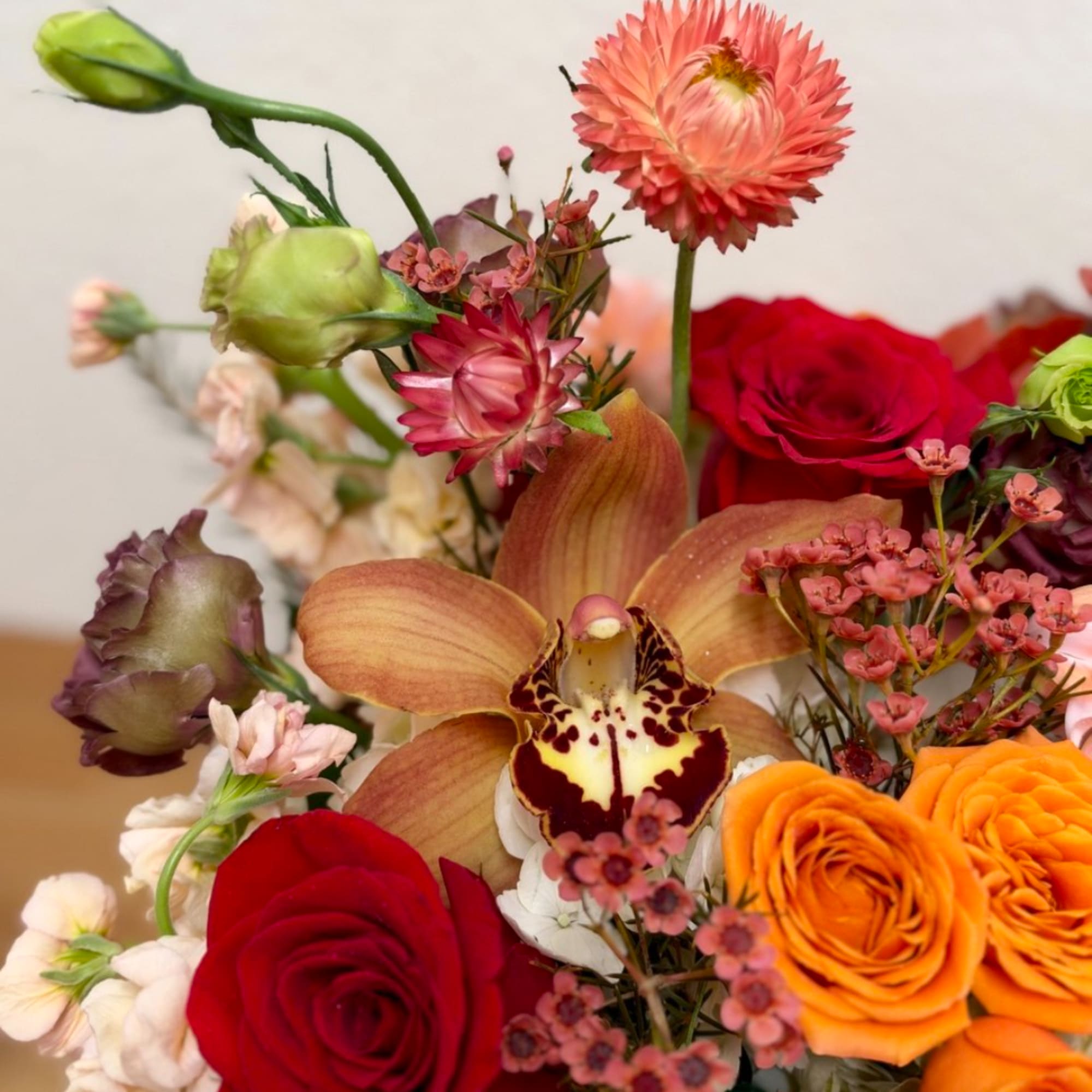 Mixed bouquet with roses, orchids, and orange blooms