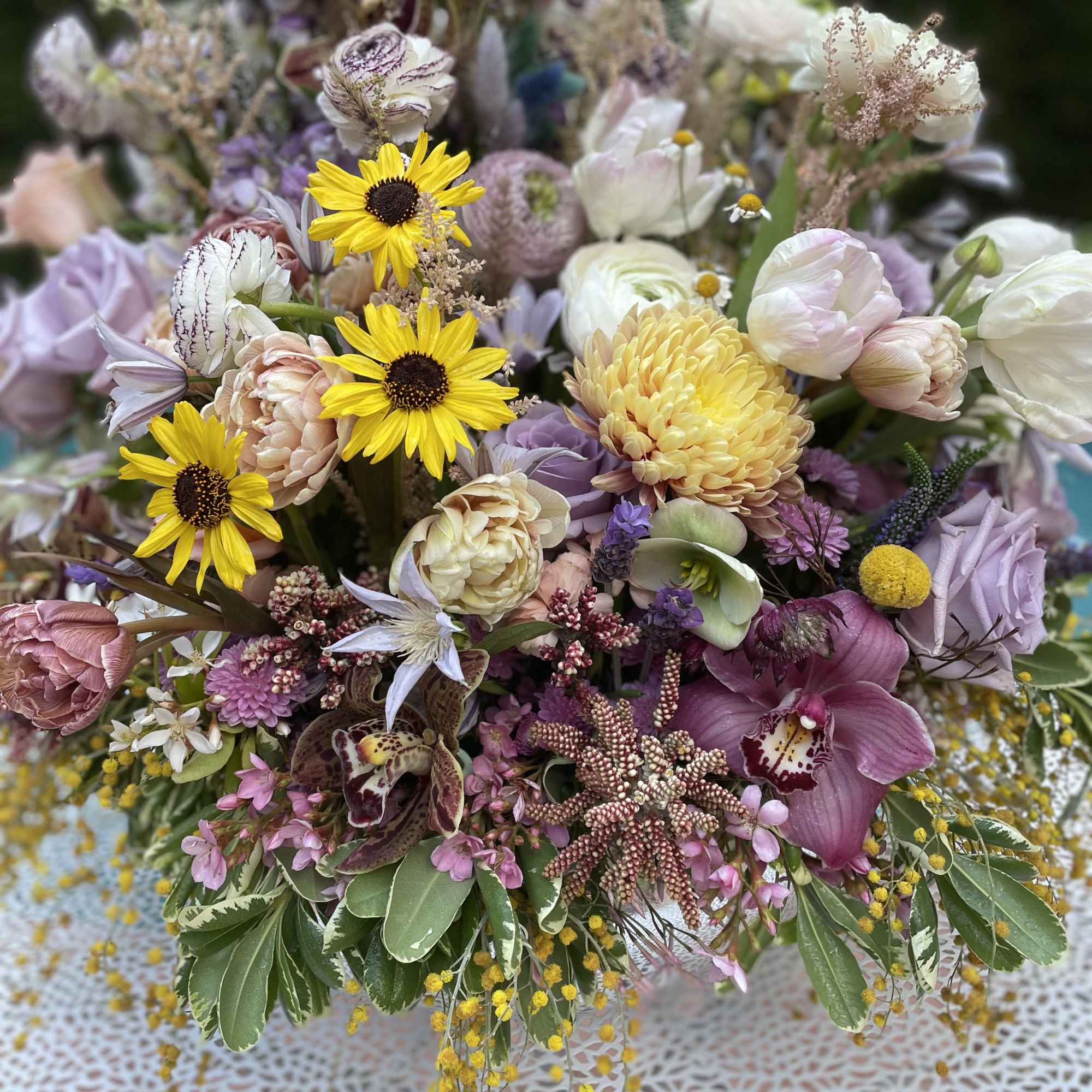 Mixed bouquet with yellow daisies, pink orchids, and pale tulips