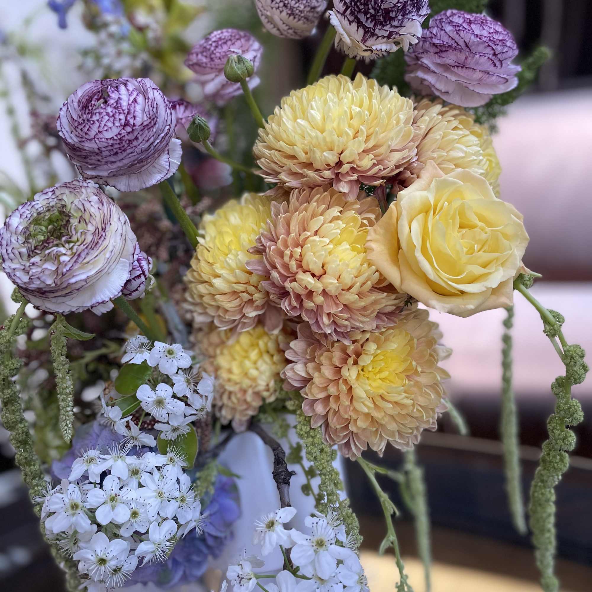 Bouquet of yellow roses, purple ranunculus, and white blossoms