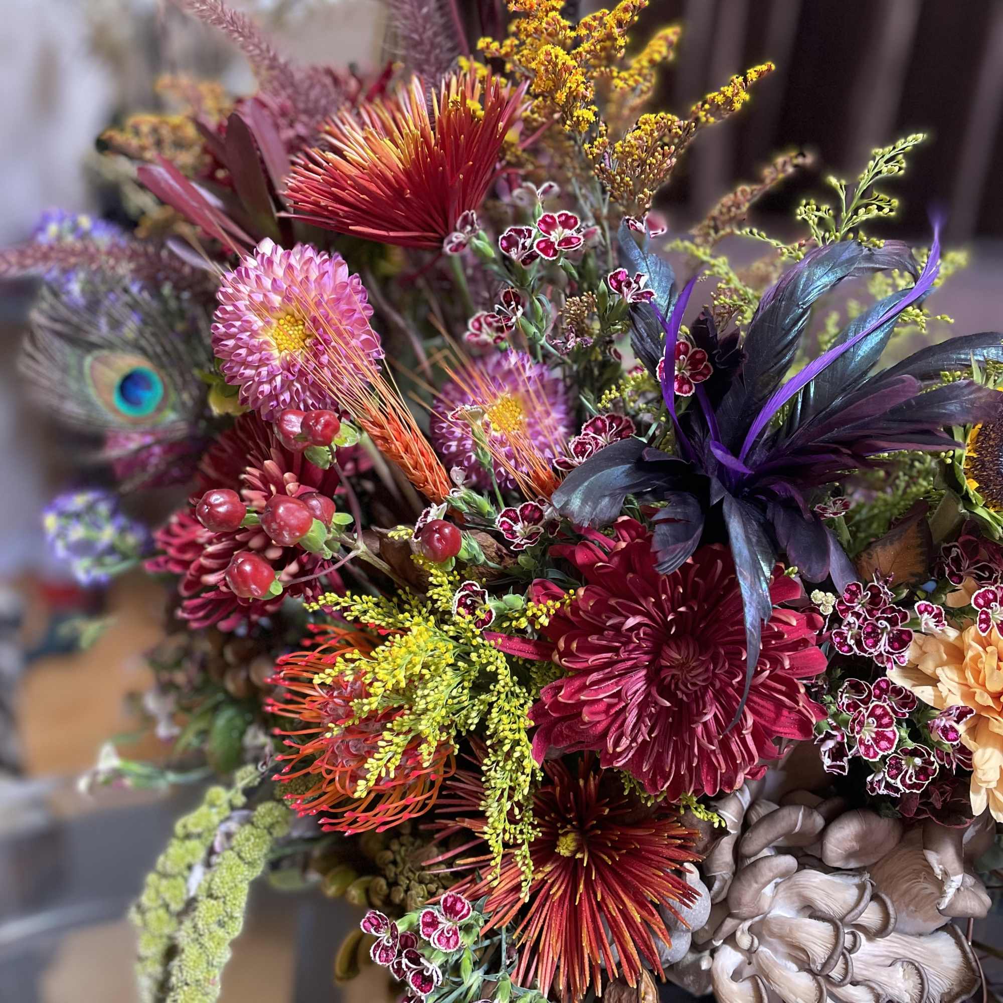 Colorful bouquet with pink, red, and orange blooms and a peacock feather