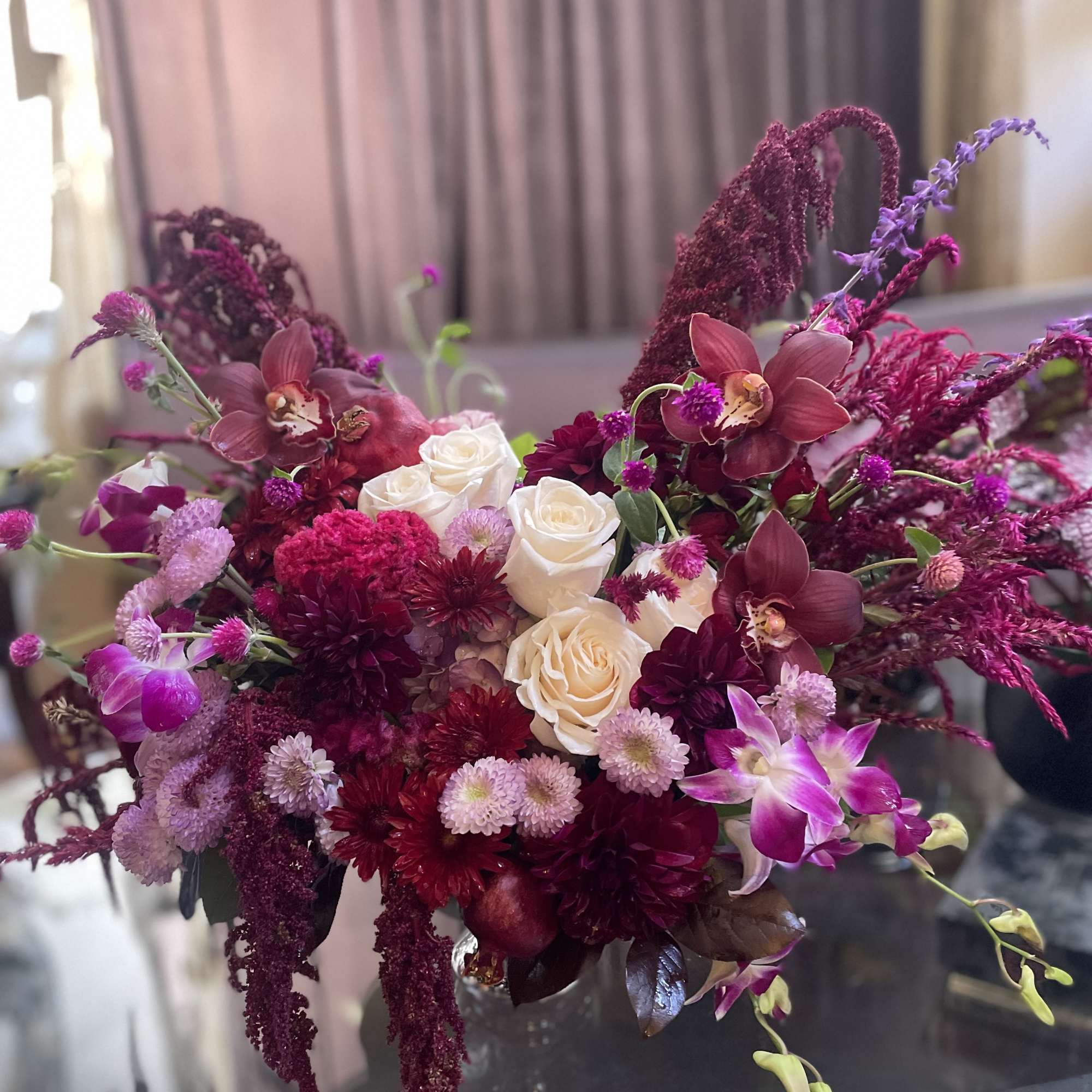 Bouquet of white roses, burgundy blooms, and purple orchids in a vase