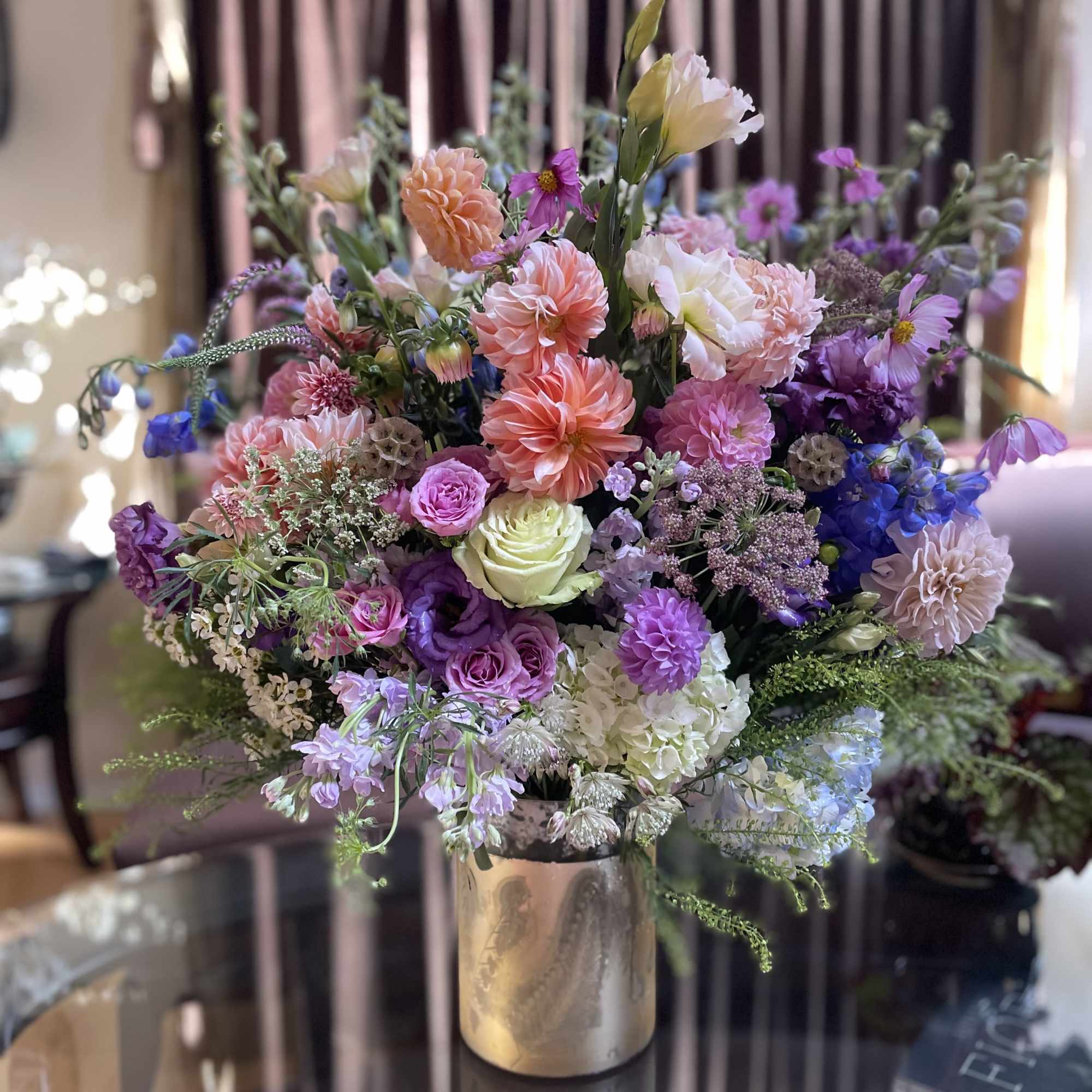 Mixed bouquet of pink, purple, and white flowers in a metallic vase
