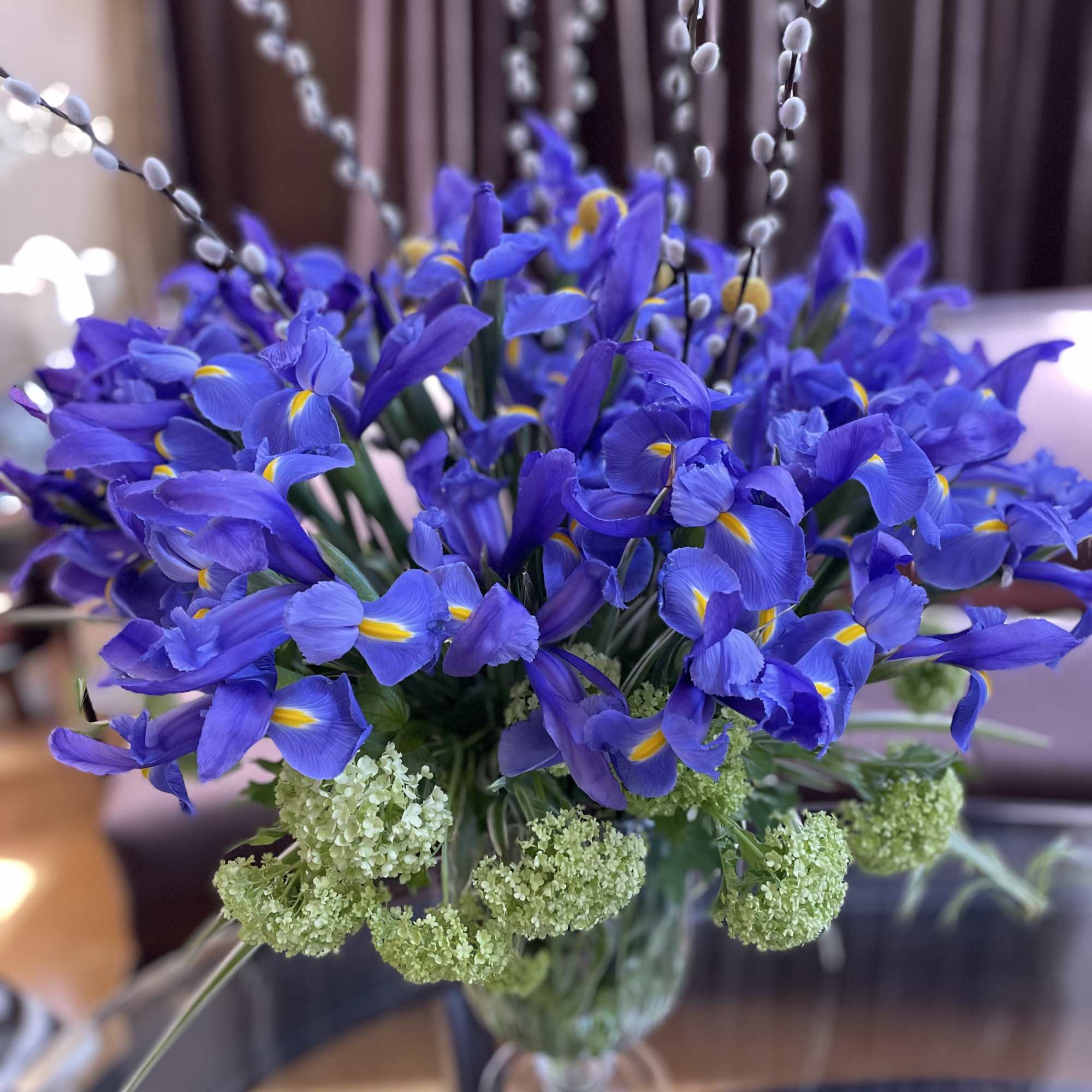 Blue iris bouquet in a glass vase with pale green filler