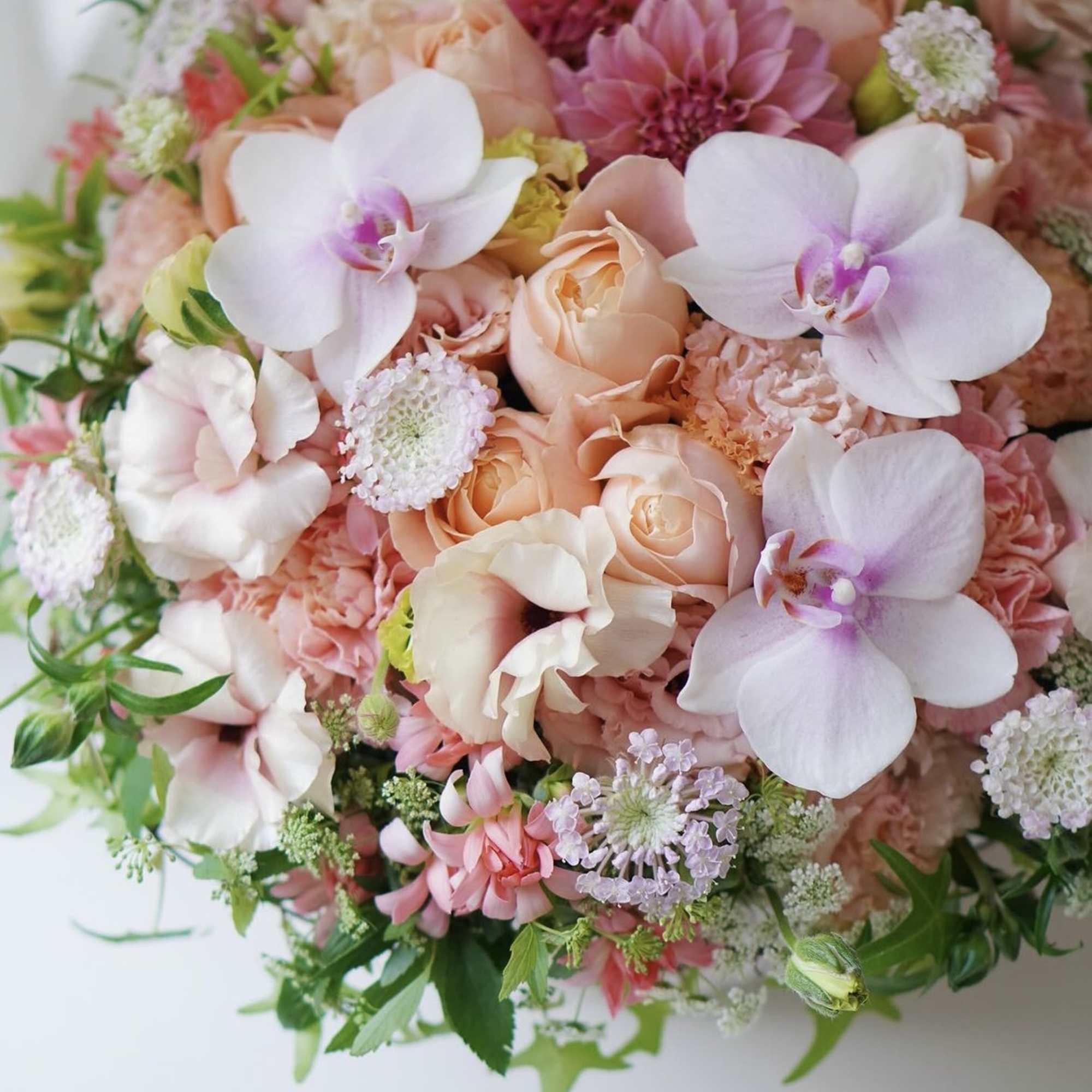 Bouquet of peach roses and white orchids with pink blooms