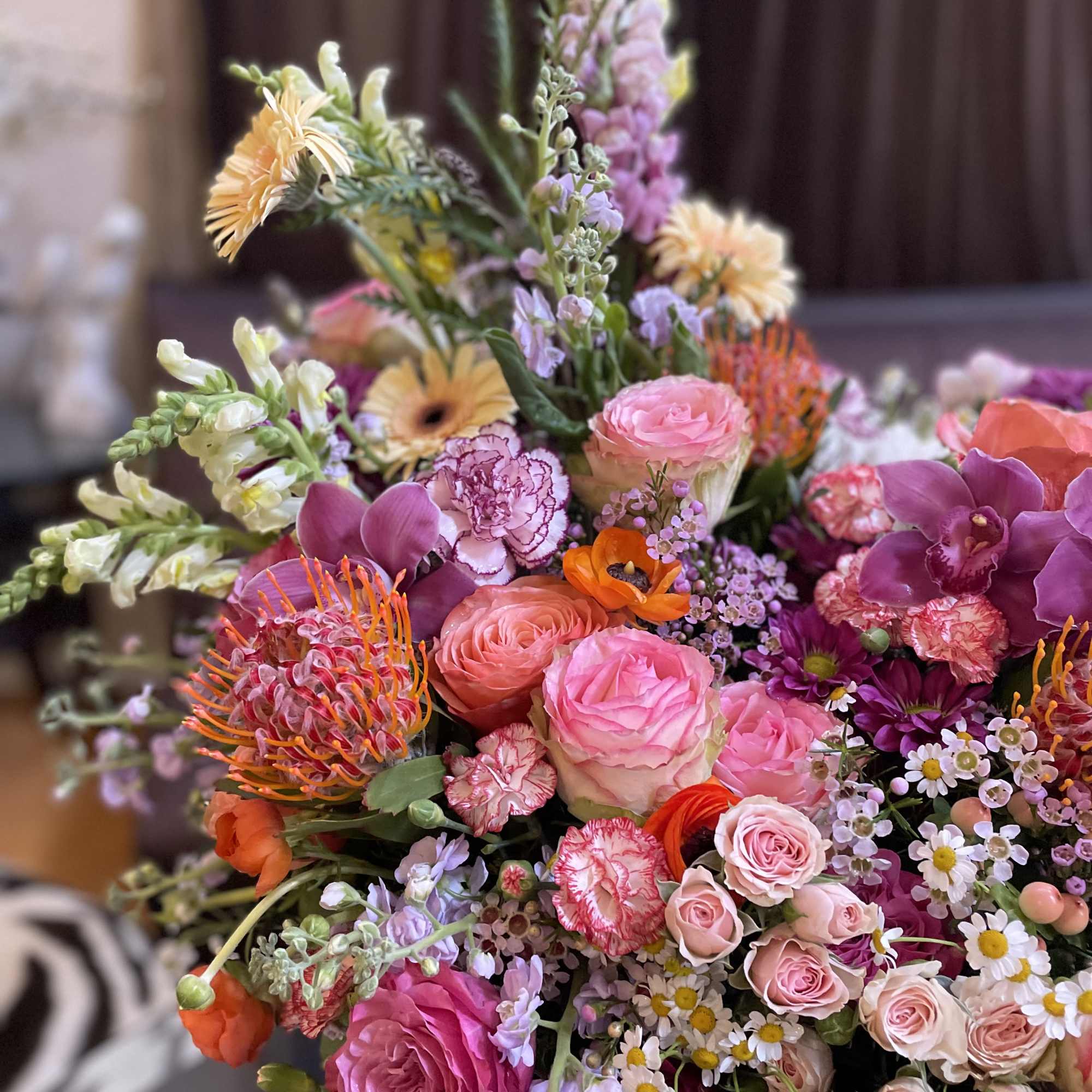 Colorful mixed bouquet with pink roses, orchids, and orange pincushion flowers