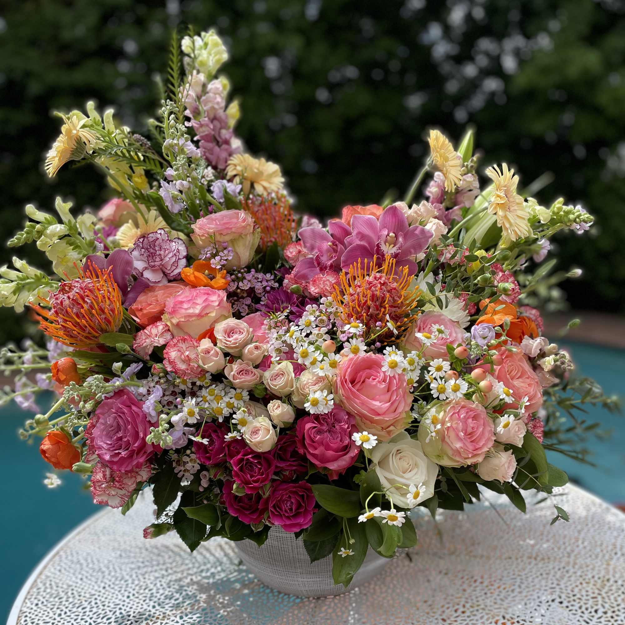 Mixed pink and orange floral arrangement in a white bowl vase