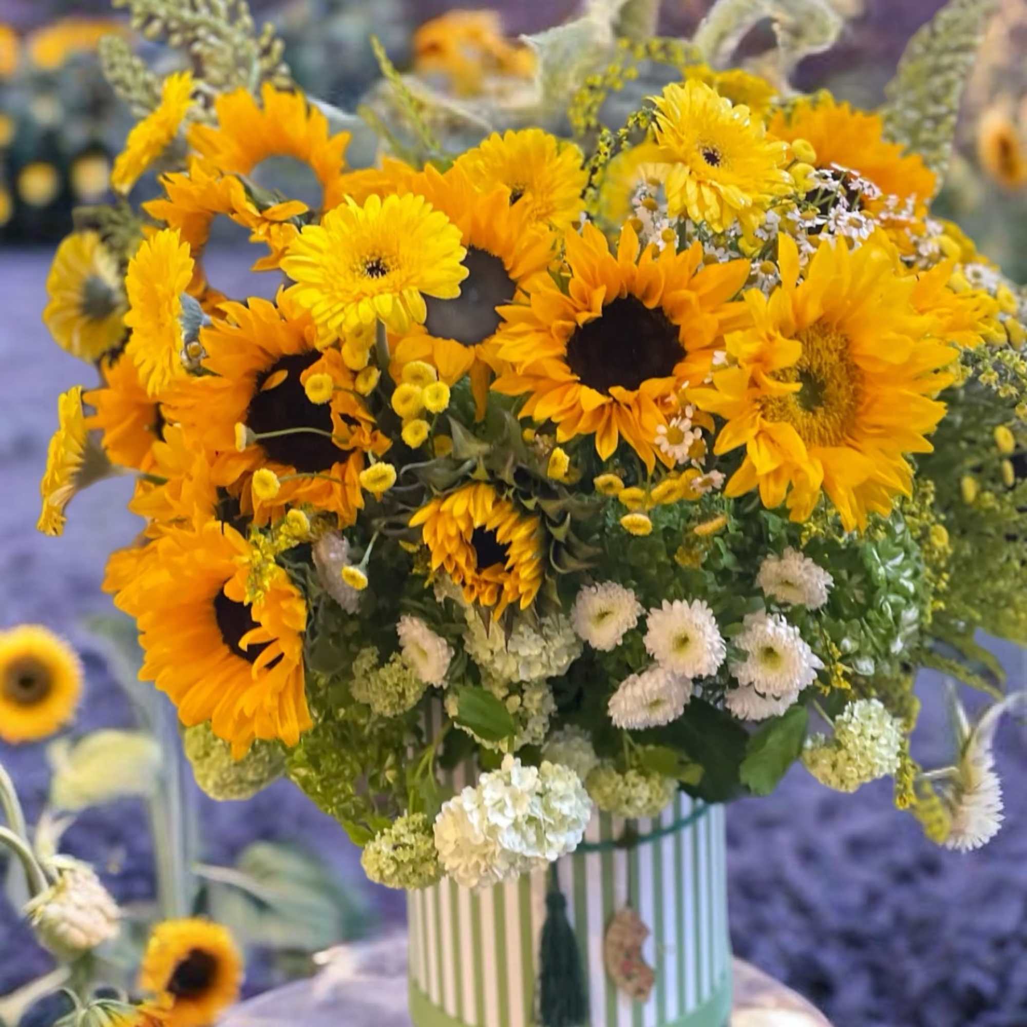 Bouquet of yellow sunflowers and white filler flowers in a striped vase