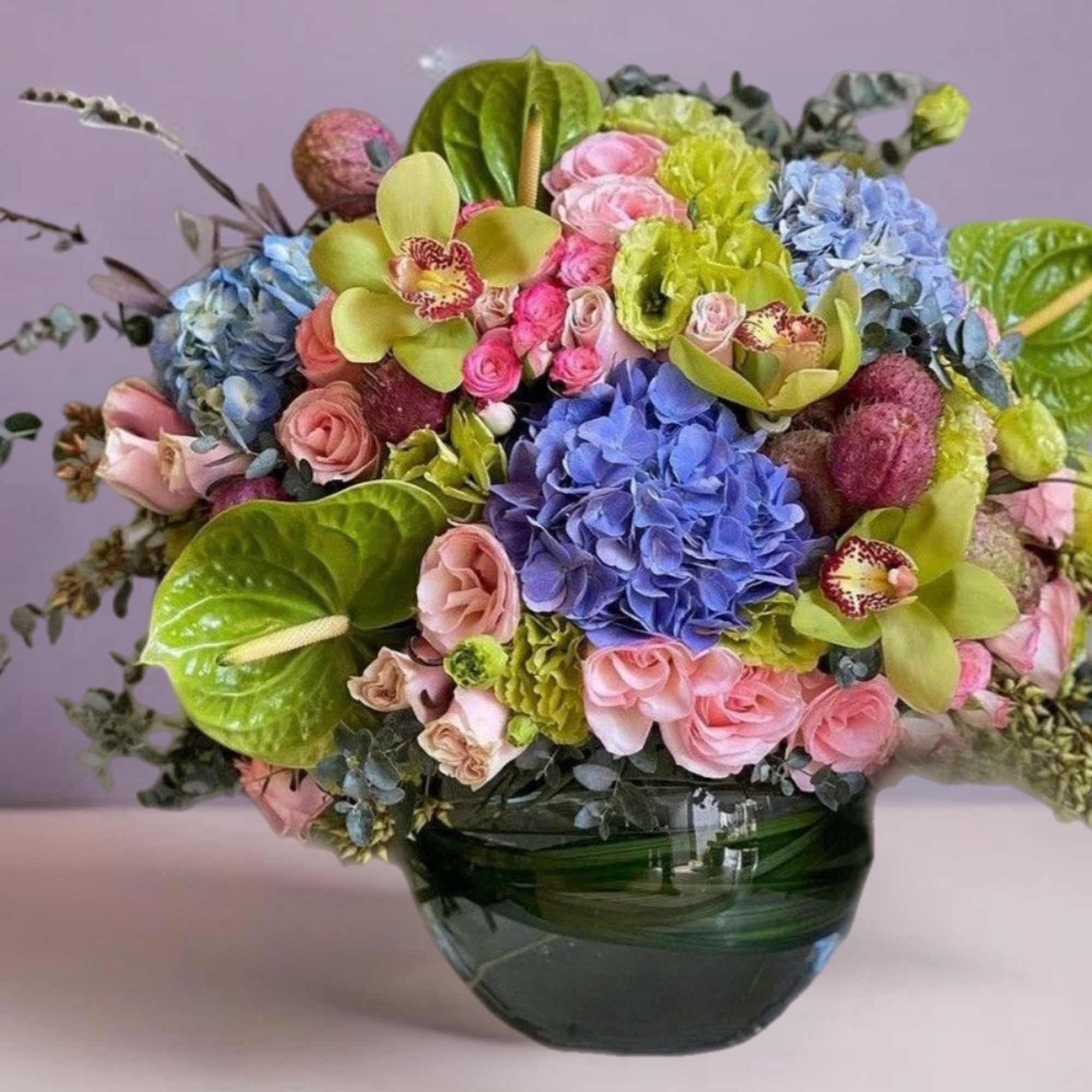 Mixed bouquet of pastel flowers in a green glass vase