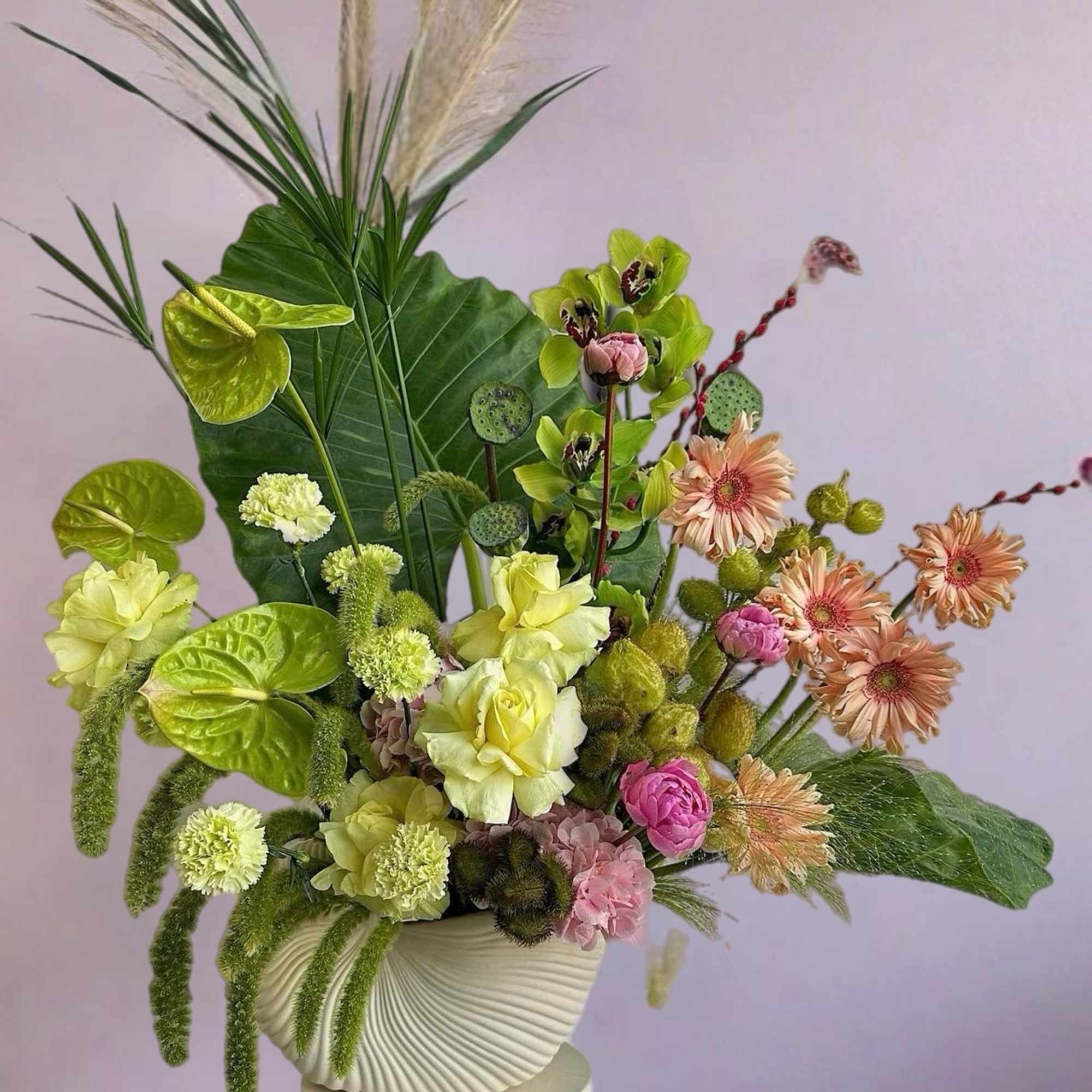 Mixed floral arrangement in a white textured vase with pink and green blooms