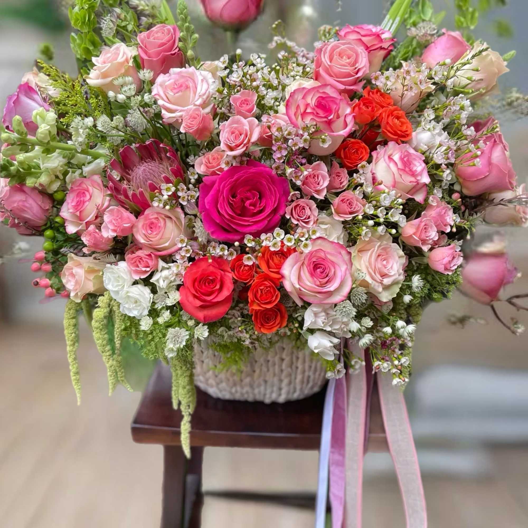 Large pink and red rose arrangement in a woven basket