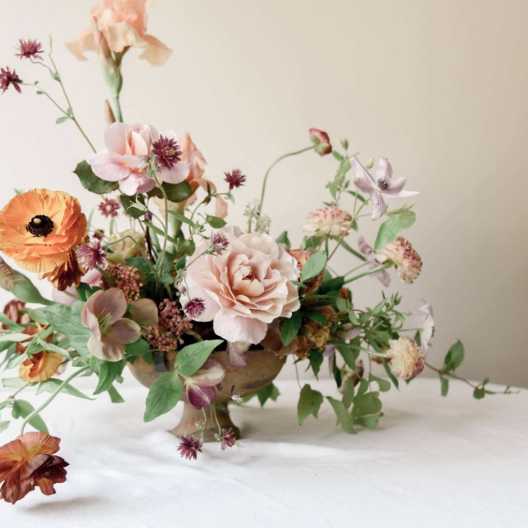 Loose pastel floral arrangement in a low pedestal bowl