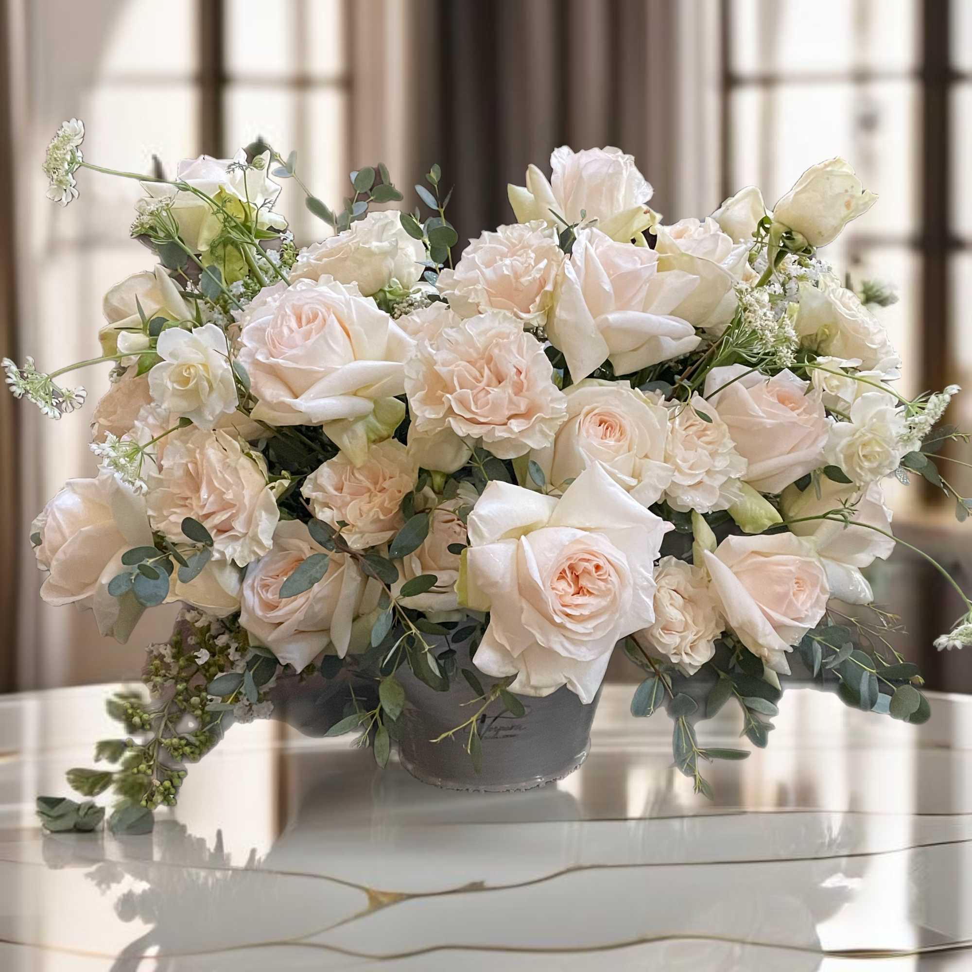 Cream roses and carnations arranged in a gray vase