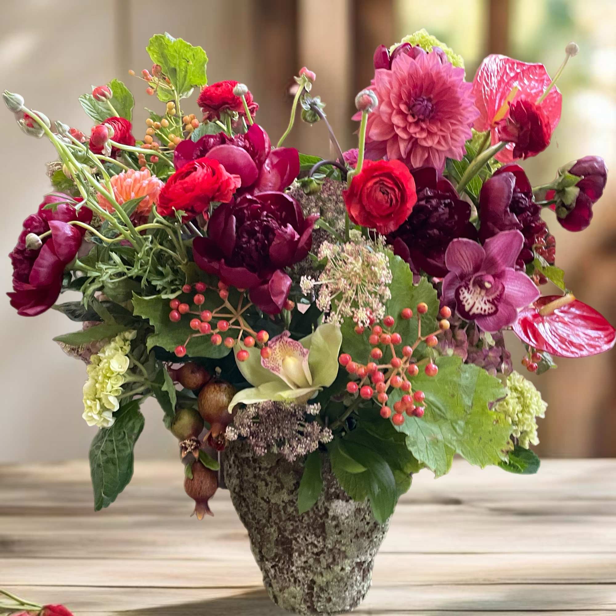 Mixed pink and burgundy flowers arranged in a stone vase