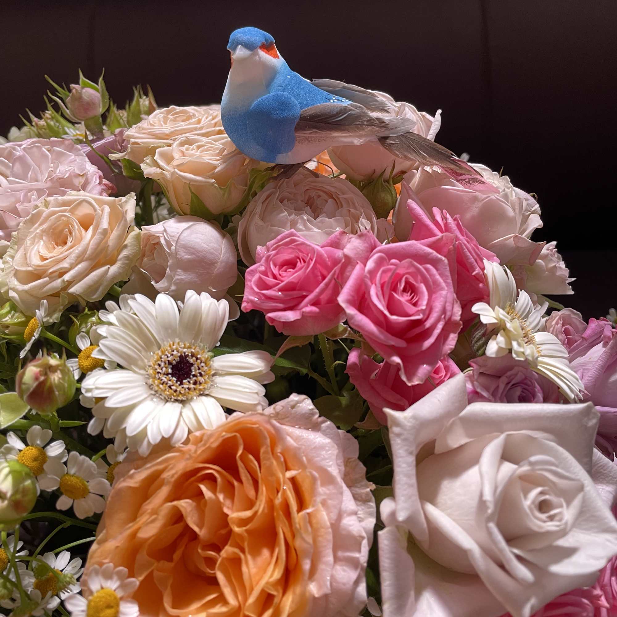Mixed bouquet of roses and daisies with a small blue bird topper