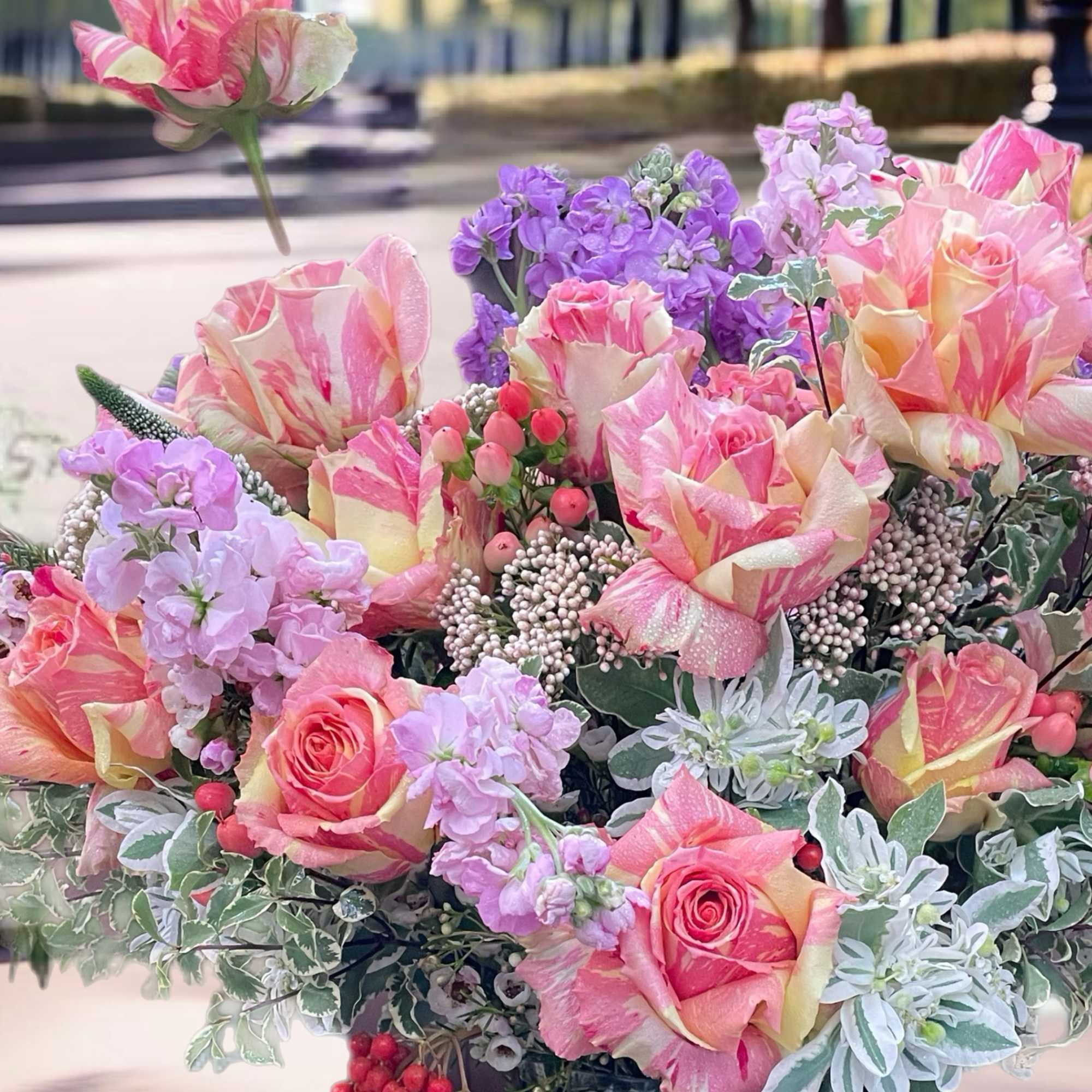 Bouquet of pink and cream roses with purple flowers in a green vase