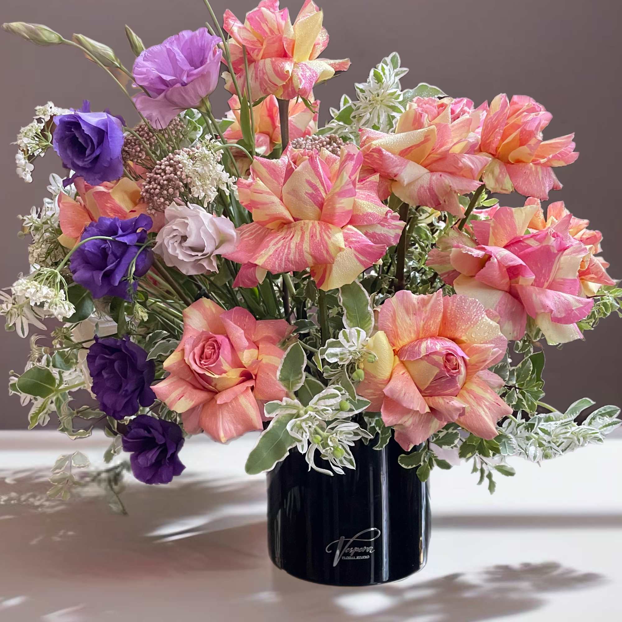 Bouquet of pink, peach, and purple flowers in a black vase