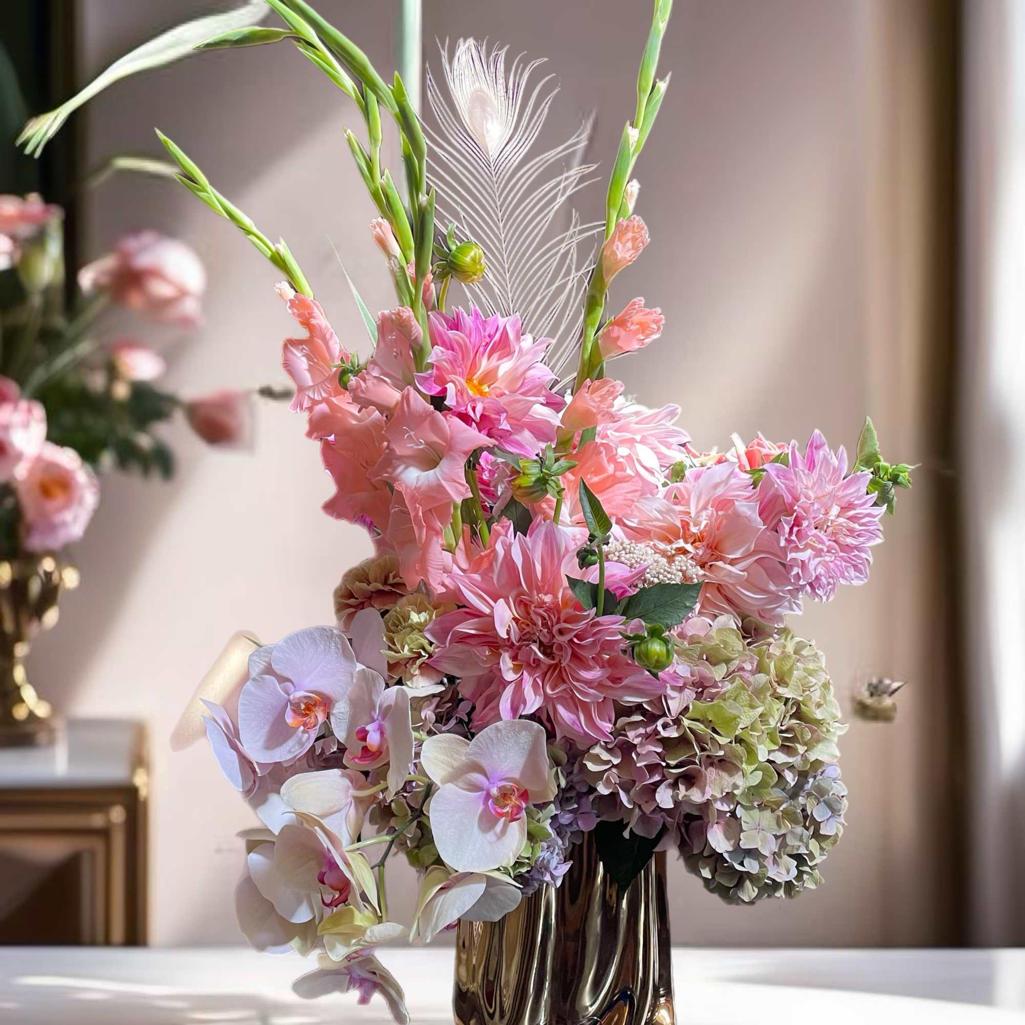 Pink floral arrangement in a metallic vase with orchids and tall stems