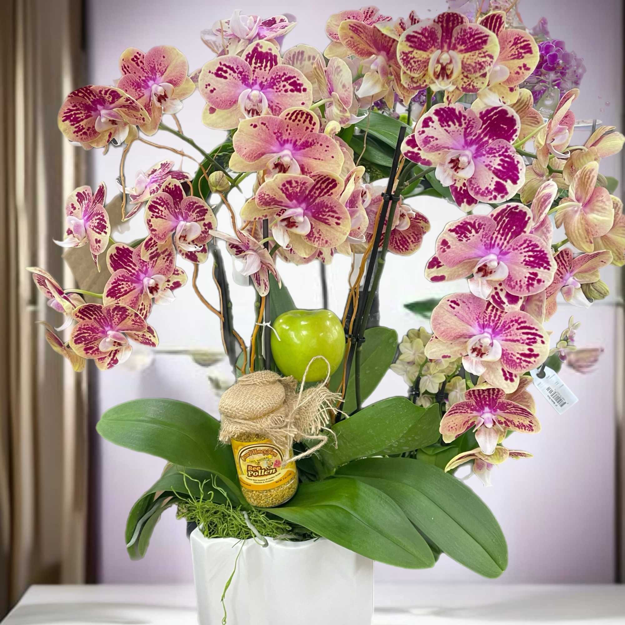 Pink and cream orchids arranged in a white pot with a small honey jar, photo 2 of 3