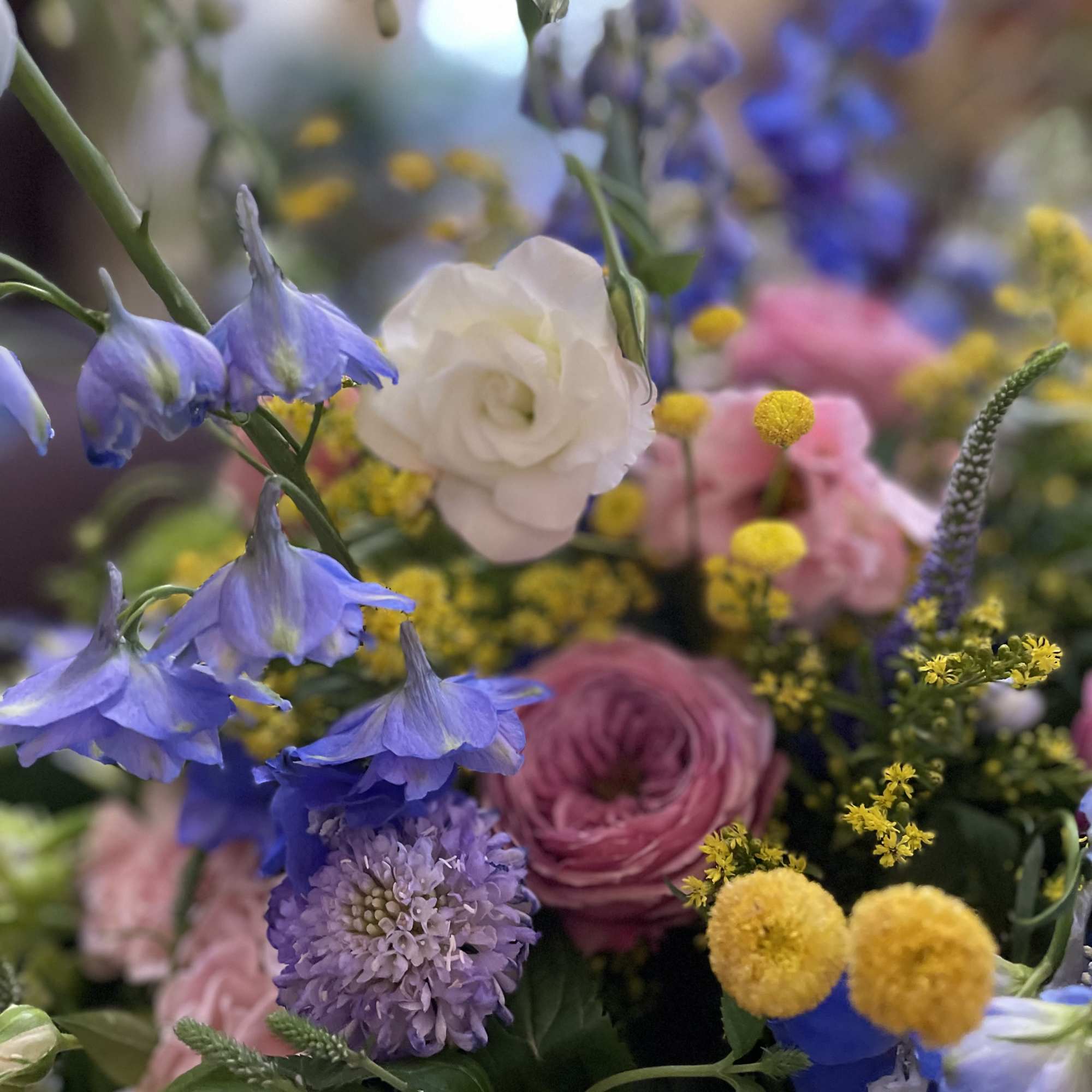Close-up bouquet with blue bell-shaped flowers, pink and white blooms, and yellow accents.