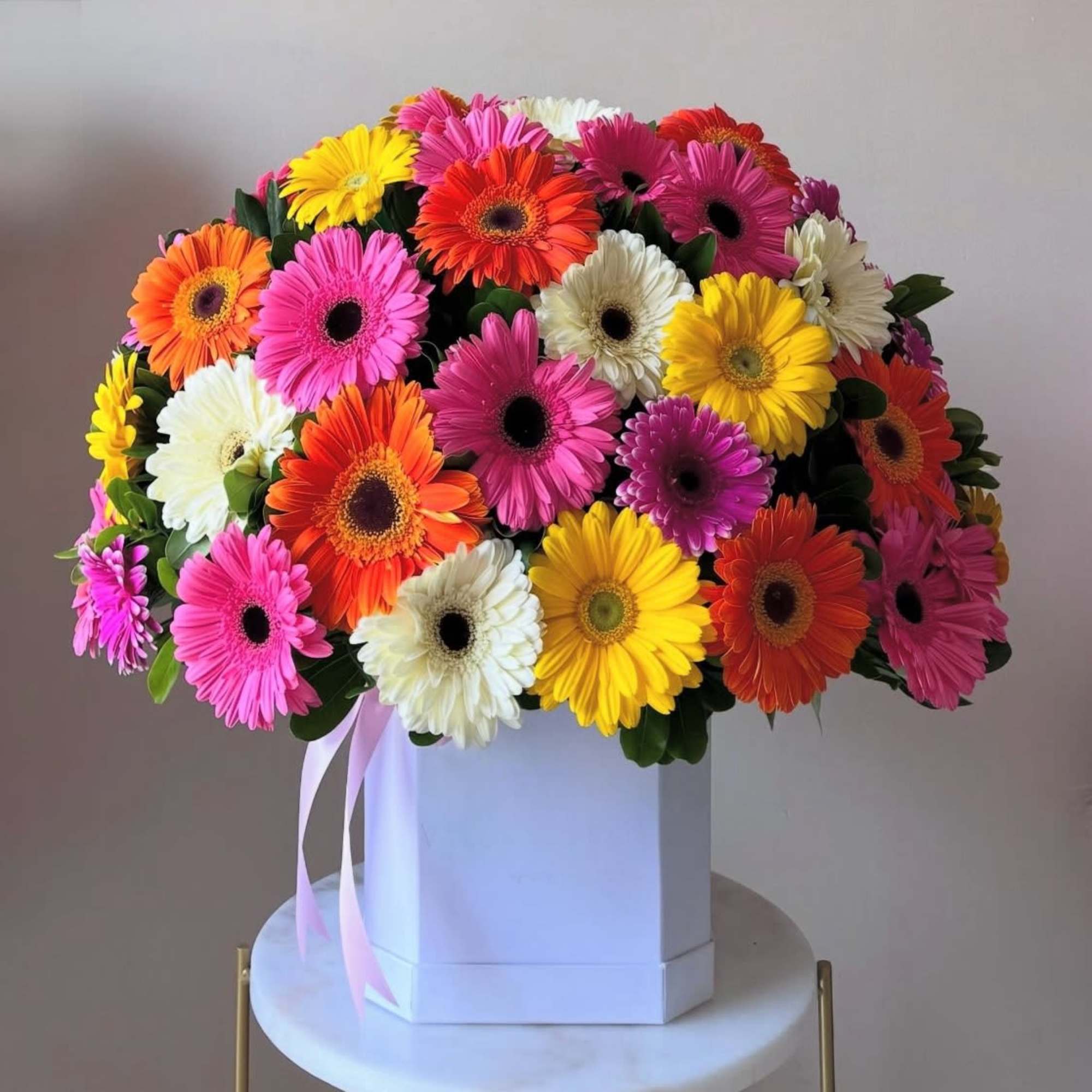Colorful gerbera daisy bouquet in a white box with pink ribbon