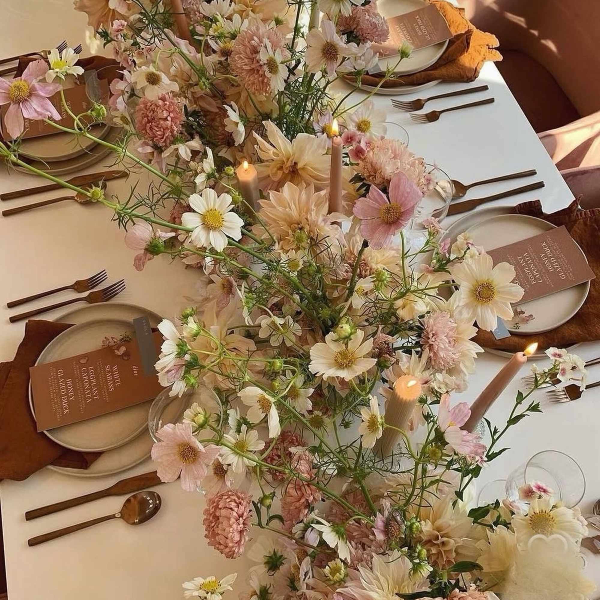 Pastel flower centerpiece running down a set table with candles