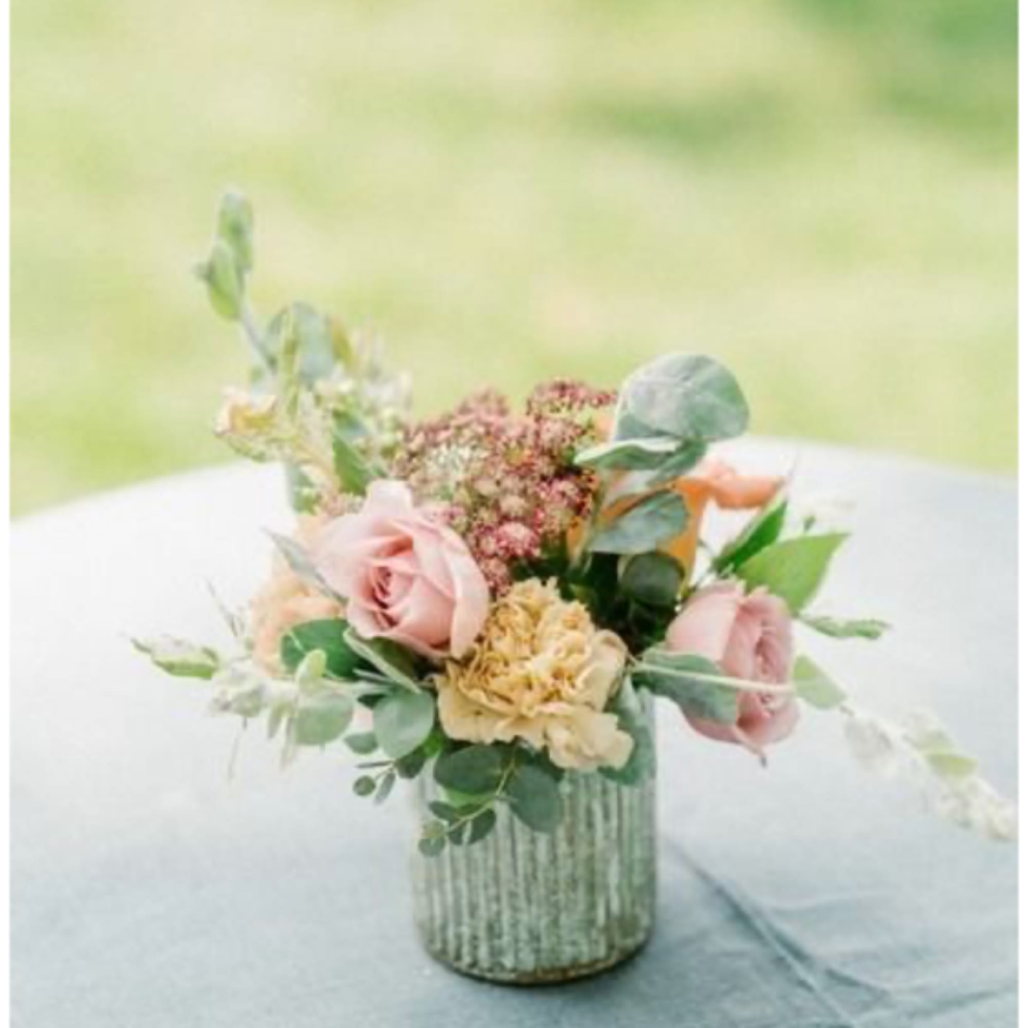 Pink roses and cream flowers in a ribbed glass vase