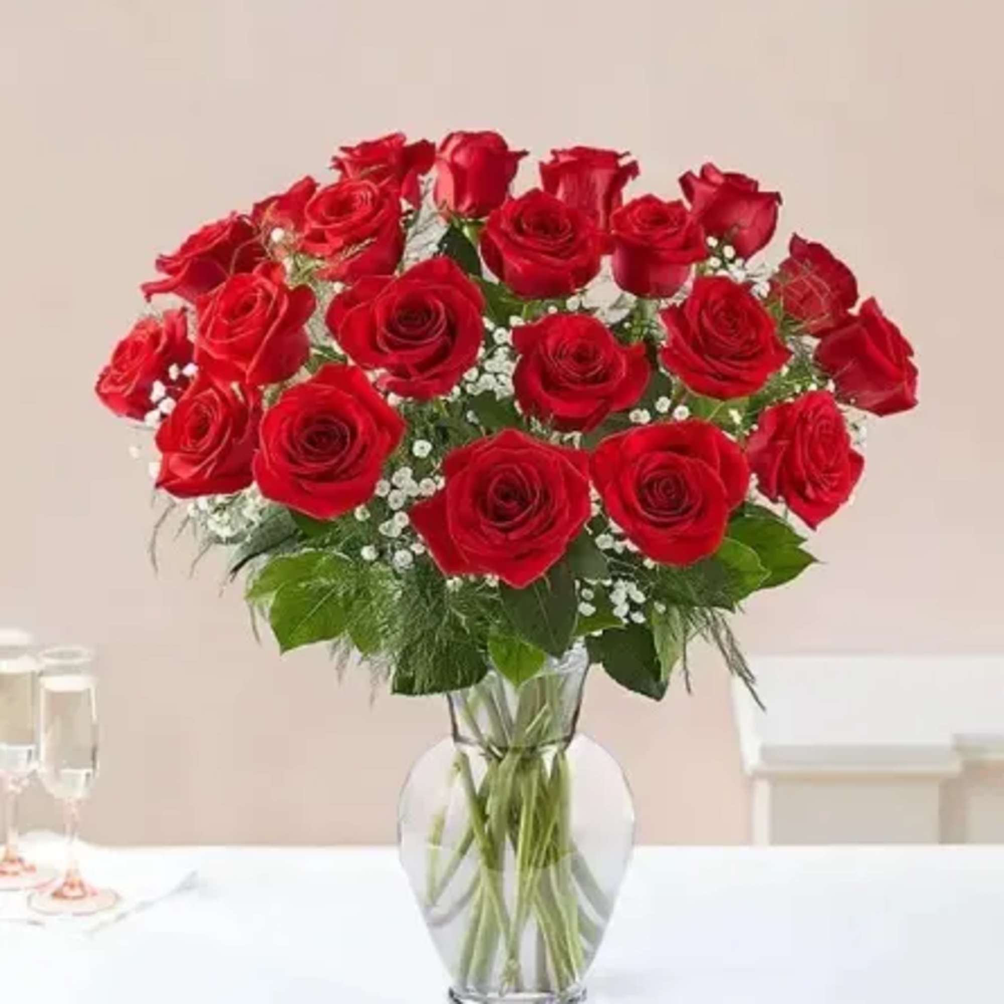 Red roses arranged in a clear glass vase with small white filler flowers