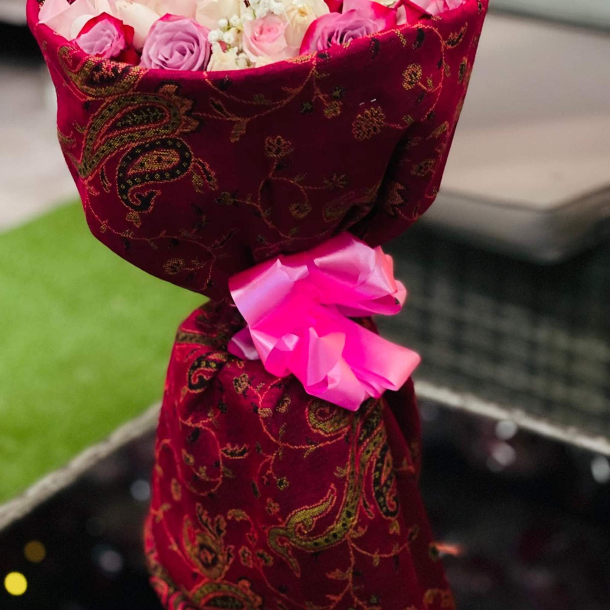 Bouquet of pink and white roses wrapped in red patterned fabric