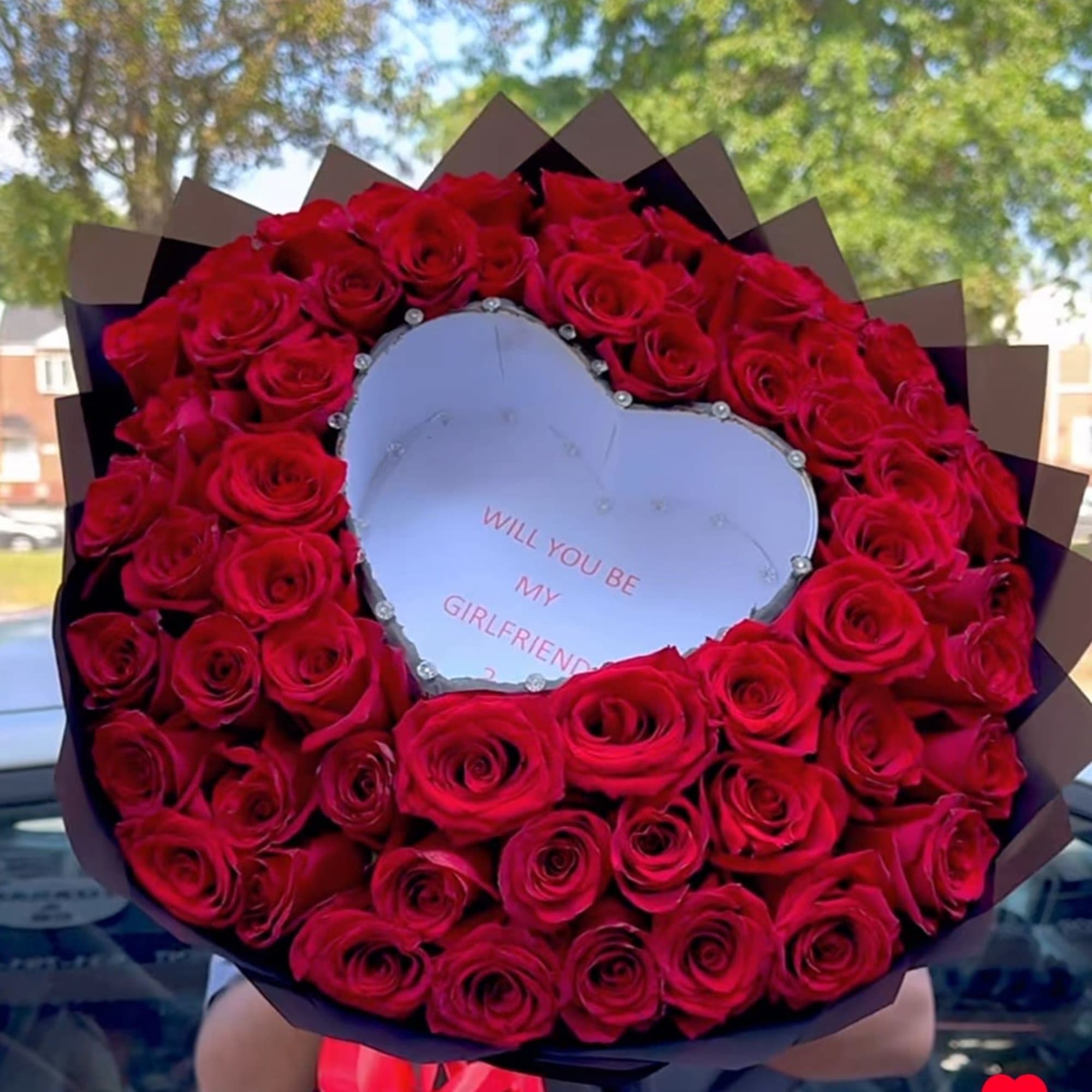 Heart-shaped bouquet of red roses with a note in the center