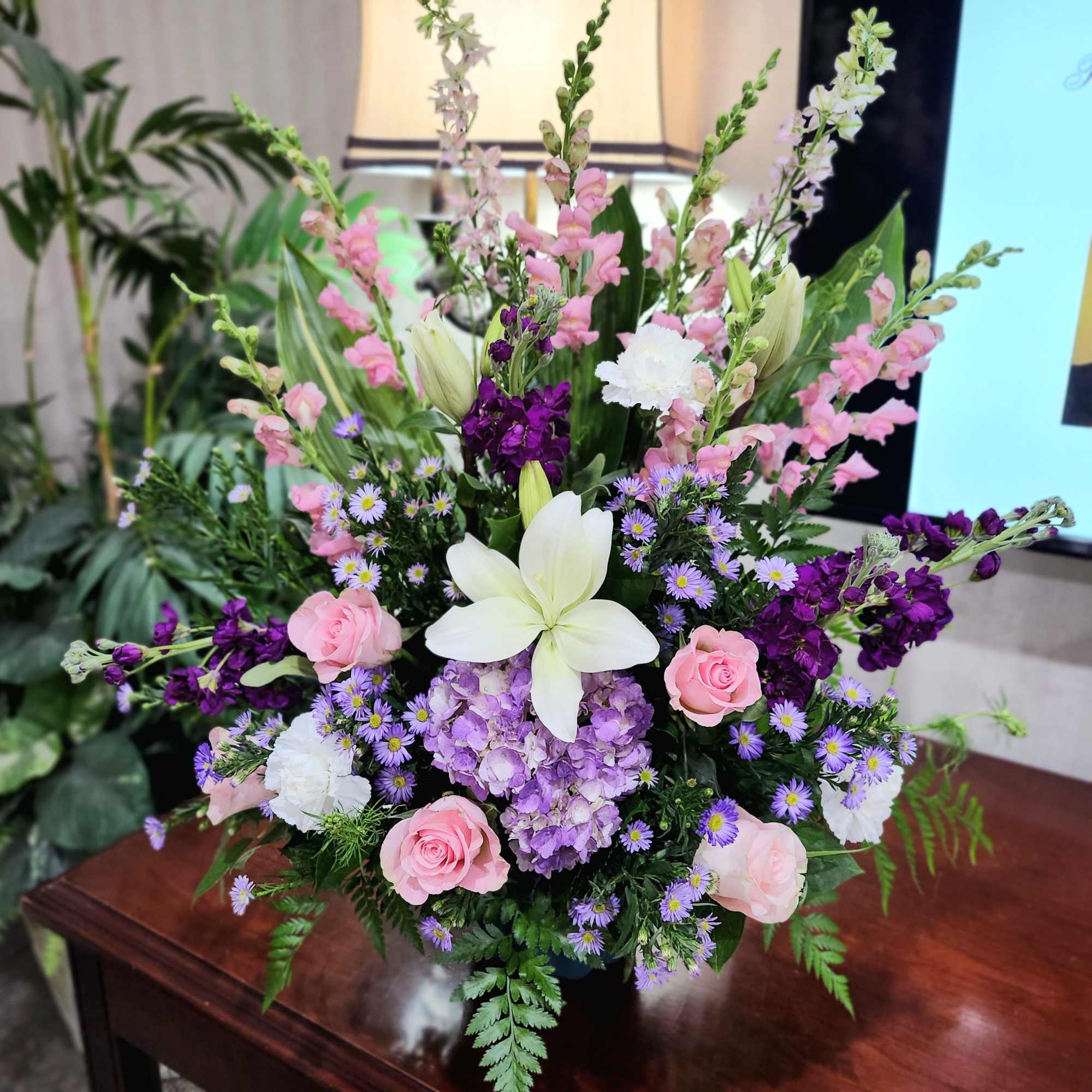 Mixed bouquet with pink roses, white lilies, and purple flowers in a vase