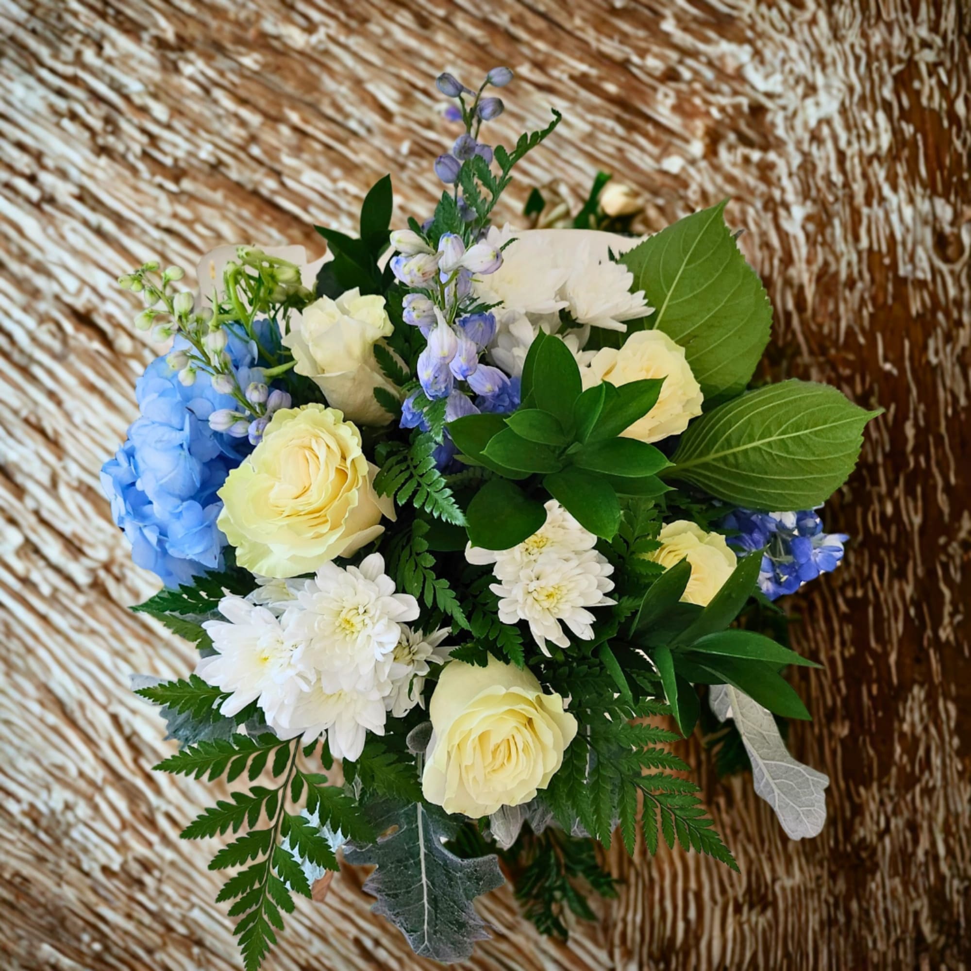 Bouquet of pale yellow roses, white daisies, and blue flowers