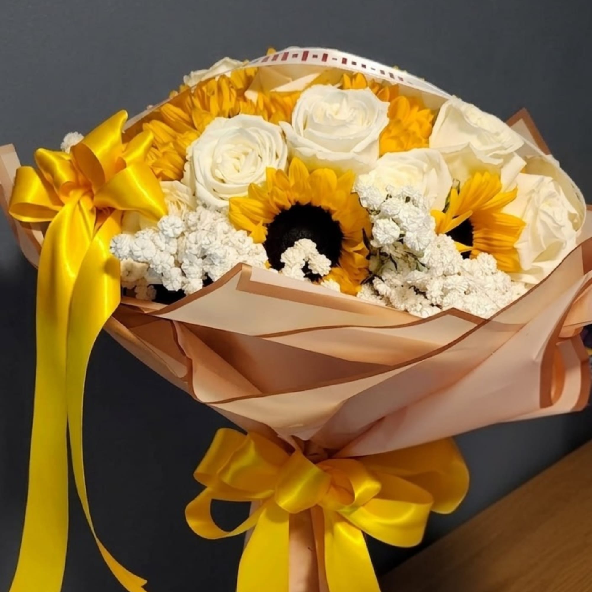 Bouquet of white roses and sunflowers wrapped with a yellow ribbon
