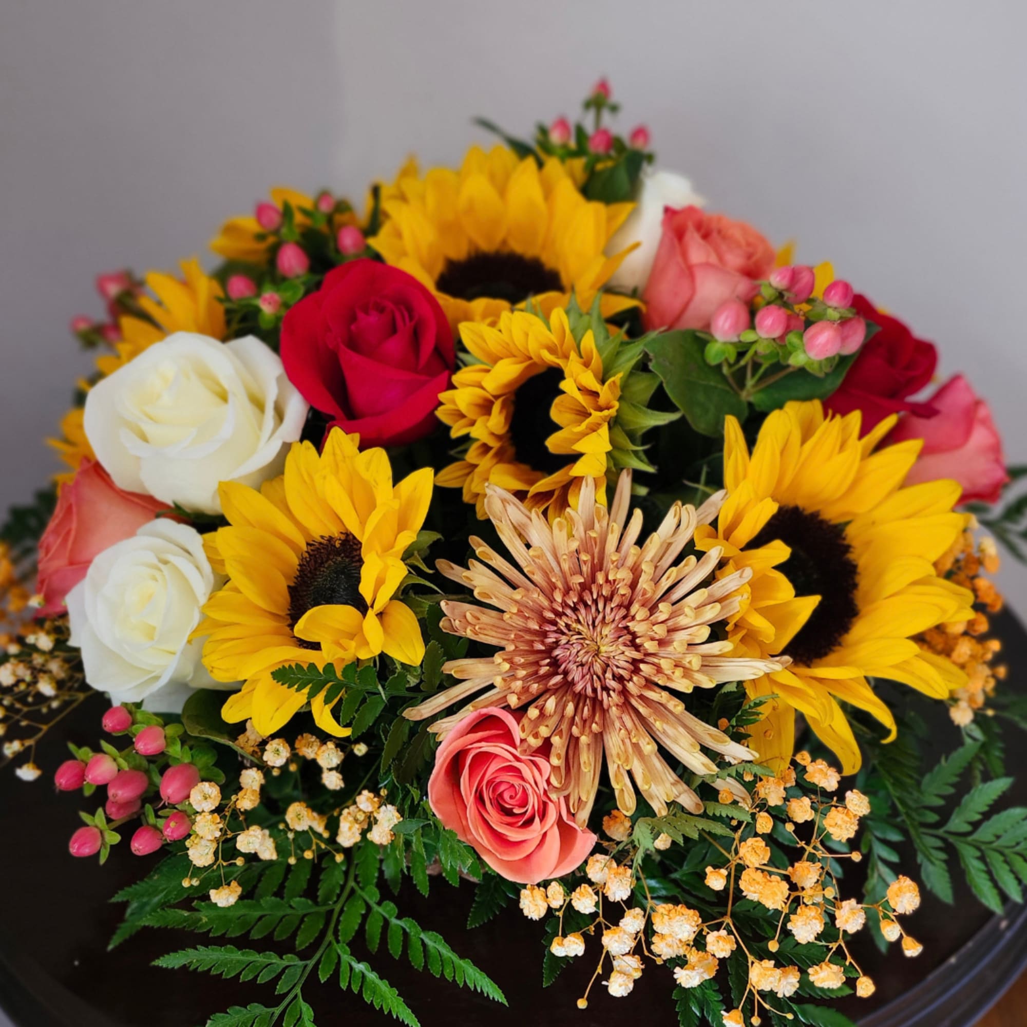 Mixed bouquet with sunflowers, roses, and small pink filler flowers