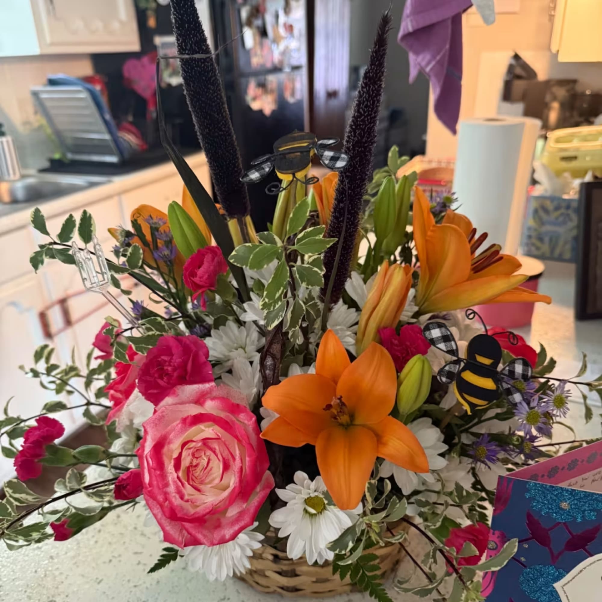 Basket arrangement with orange lilies, pink roses, and white daisies