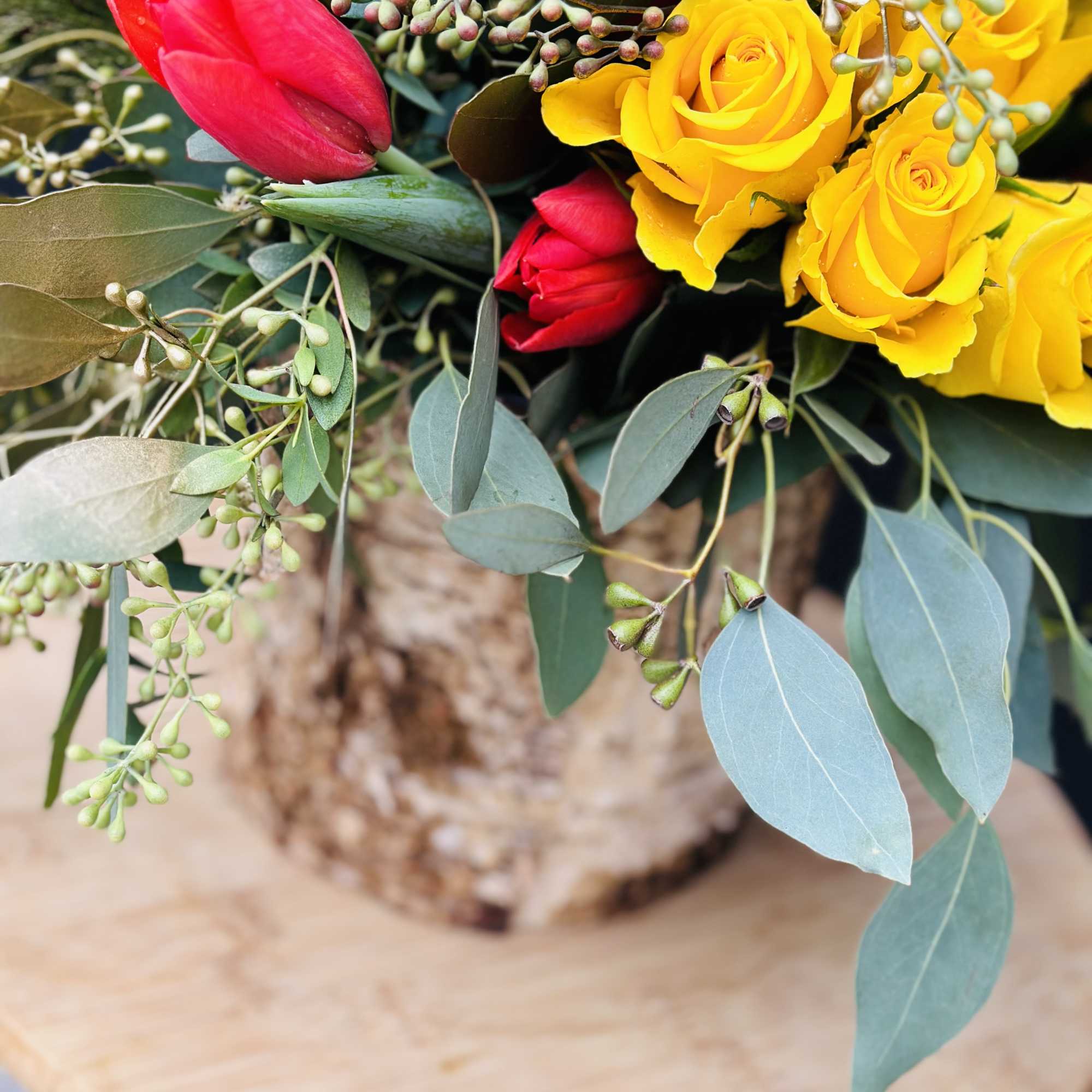 Bouquet of yellow and red roses with eucalyptus in a rustic wrap