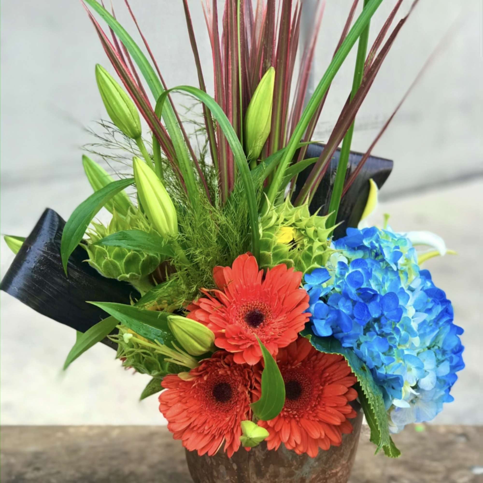 Bright mixed bouquet with red gerberas and blue hydrangea in a brown vase