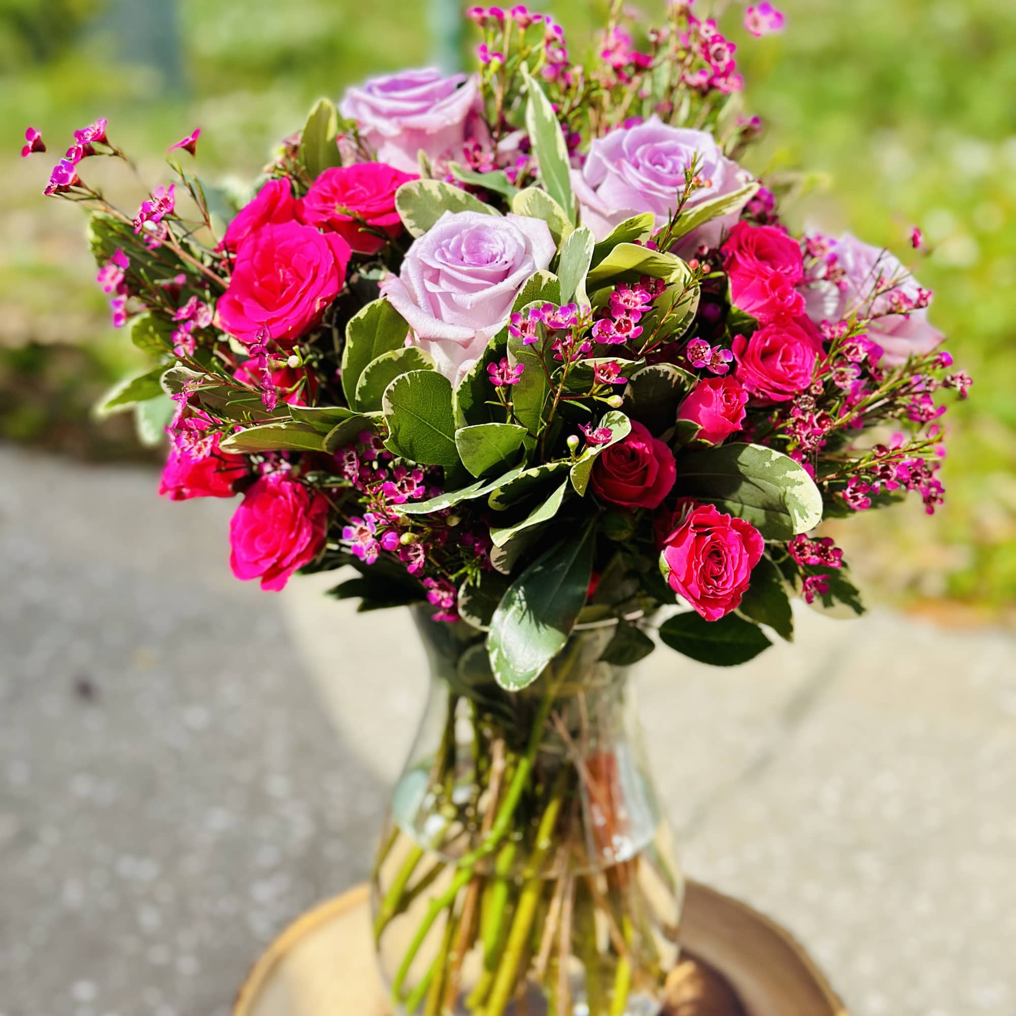 Pink and lavender roses arranged in a clear glass vase