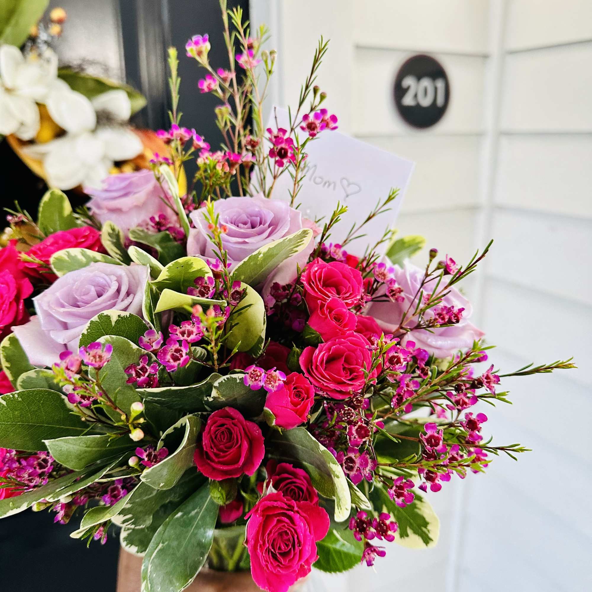 Handheld bouquet of pink and lavender roses with small magenta filler flowers