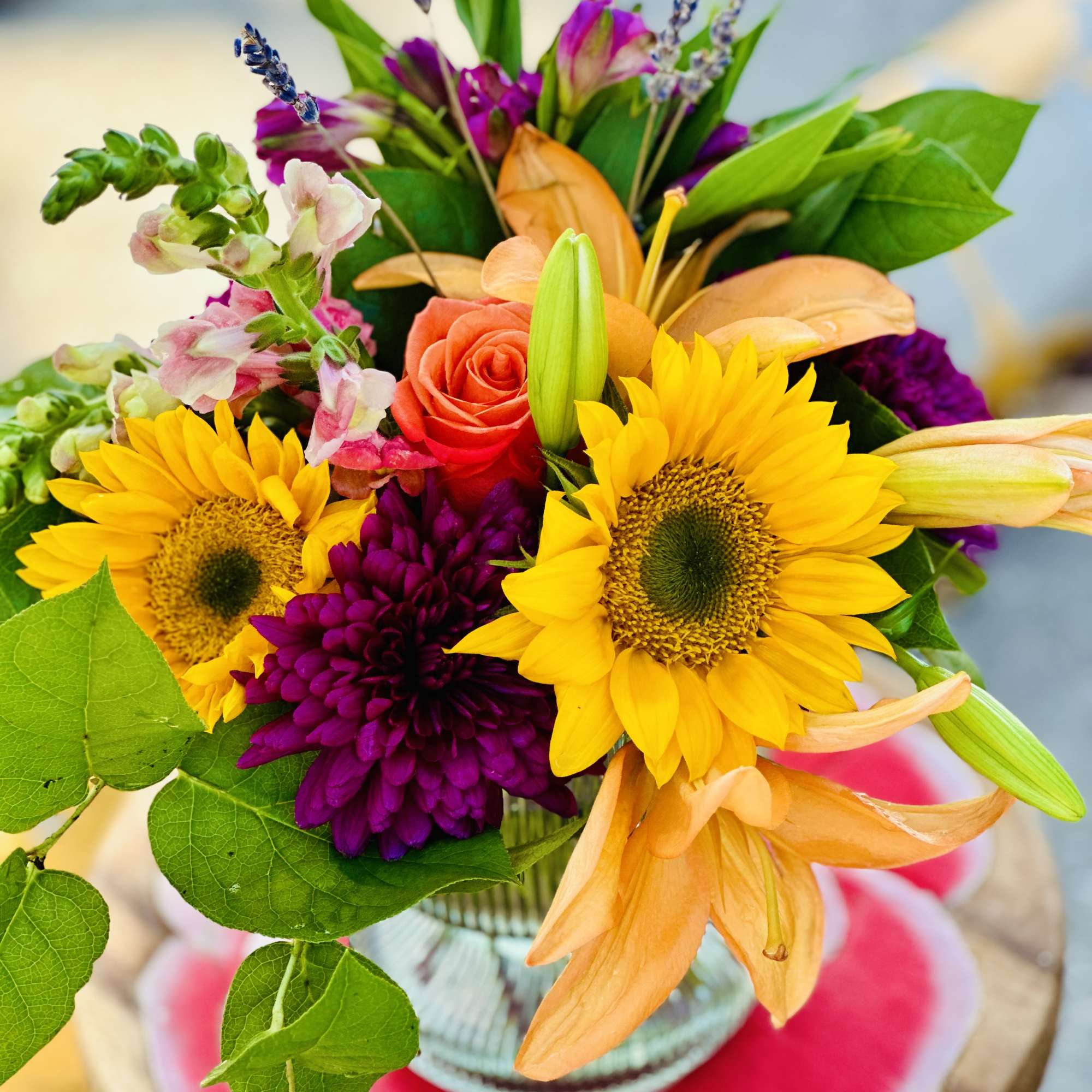 Bouquet with sunflowers, roses, and orange lilies in a glass vase