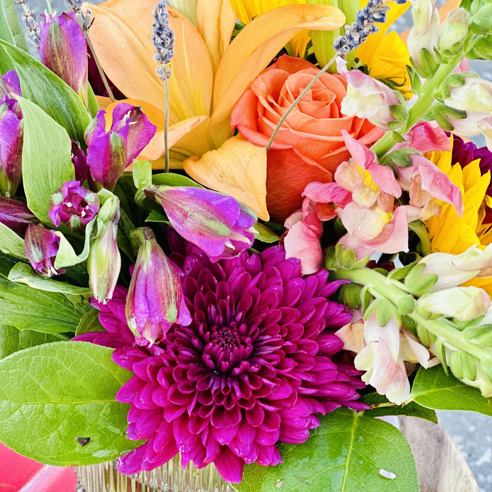 Colorful mixed bouquet with roses, lilies, and chrysanthemums in a glass vase