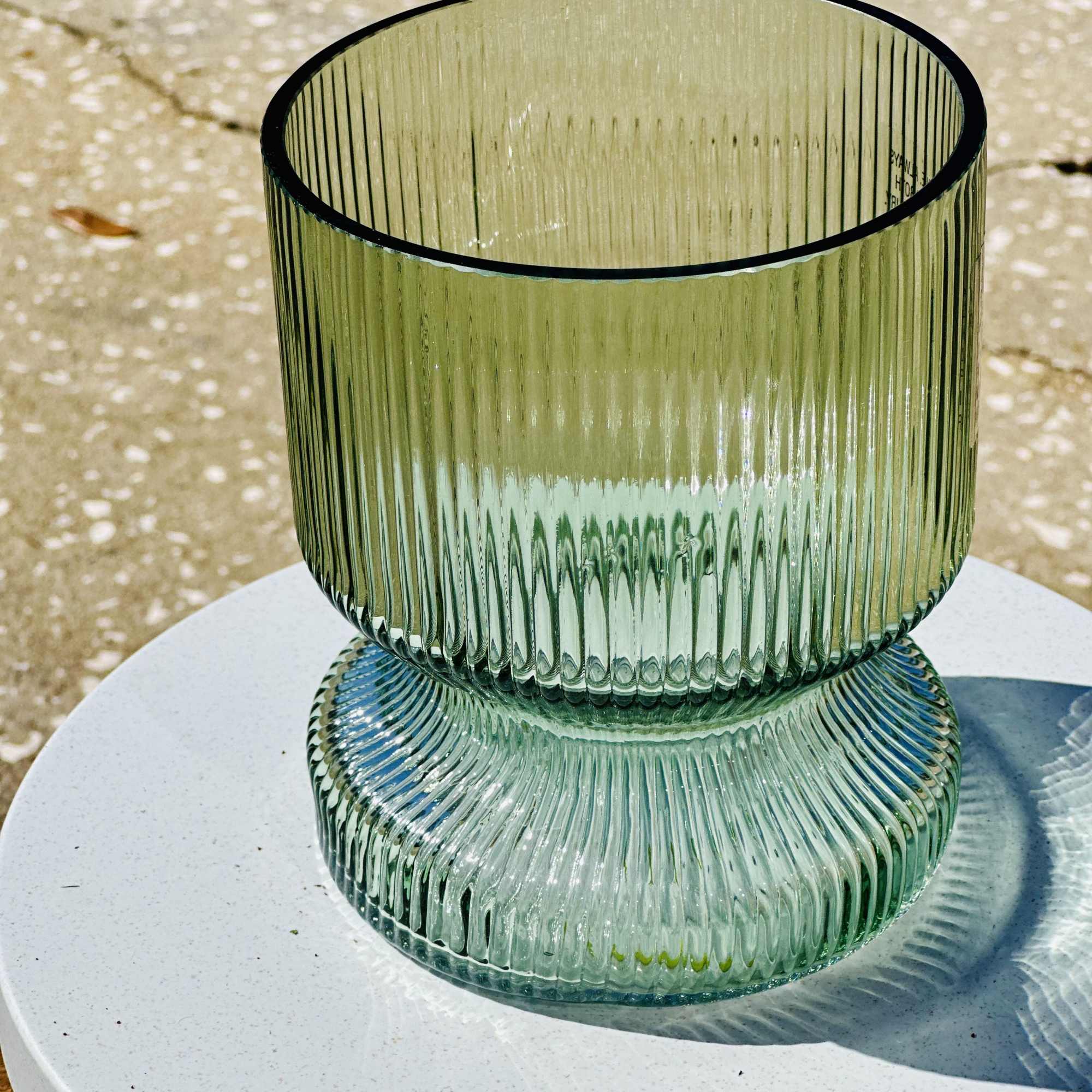 Green ribbed glass vase on a white surface