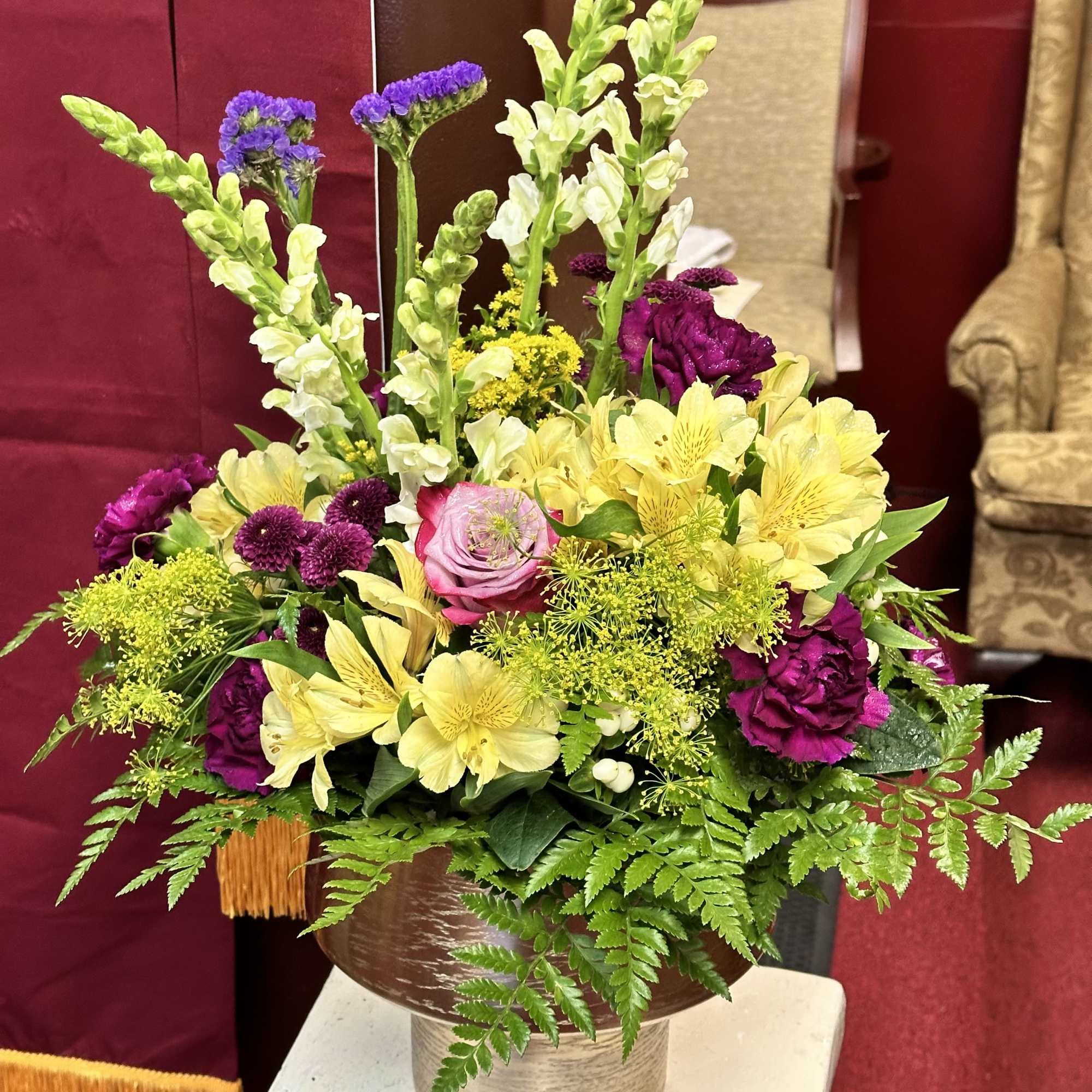 Mixed bouquet of yellow and purple flowers in a bronze vase
