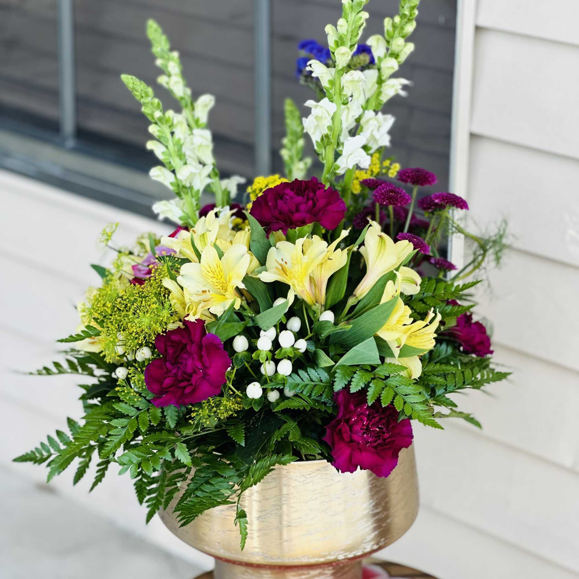 Mixed bouquet in a gold vase with yellow, magenta, and white flowers