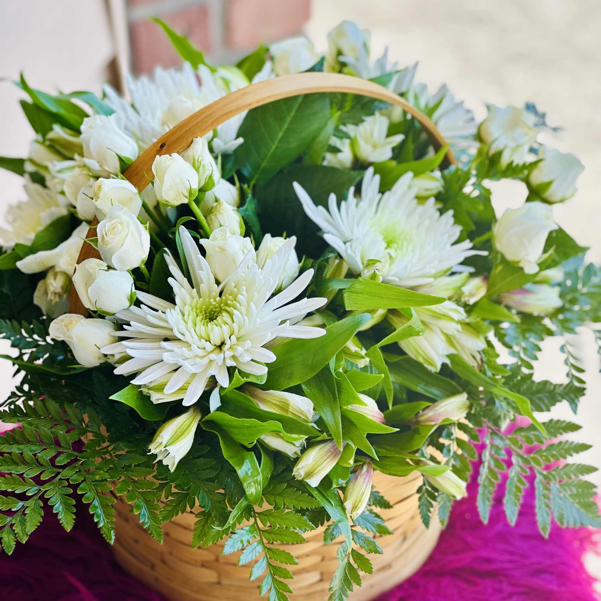 Basket of white flowers with green foliage and a wooden handle