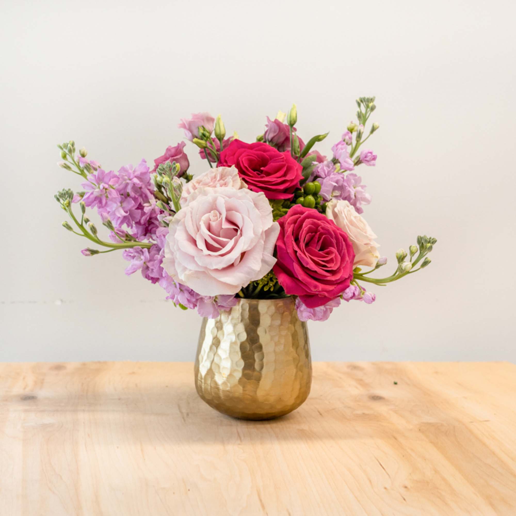 Pink and lavender roses in a gold hammered vase