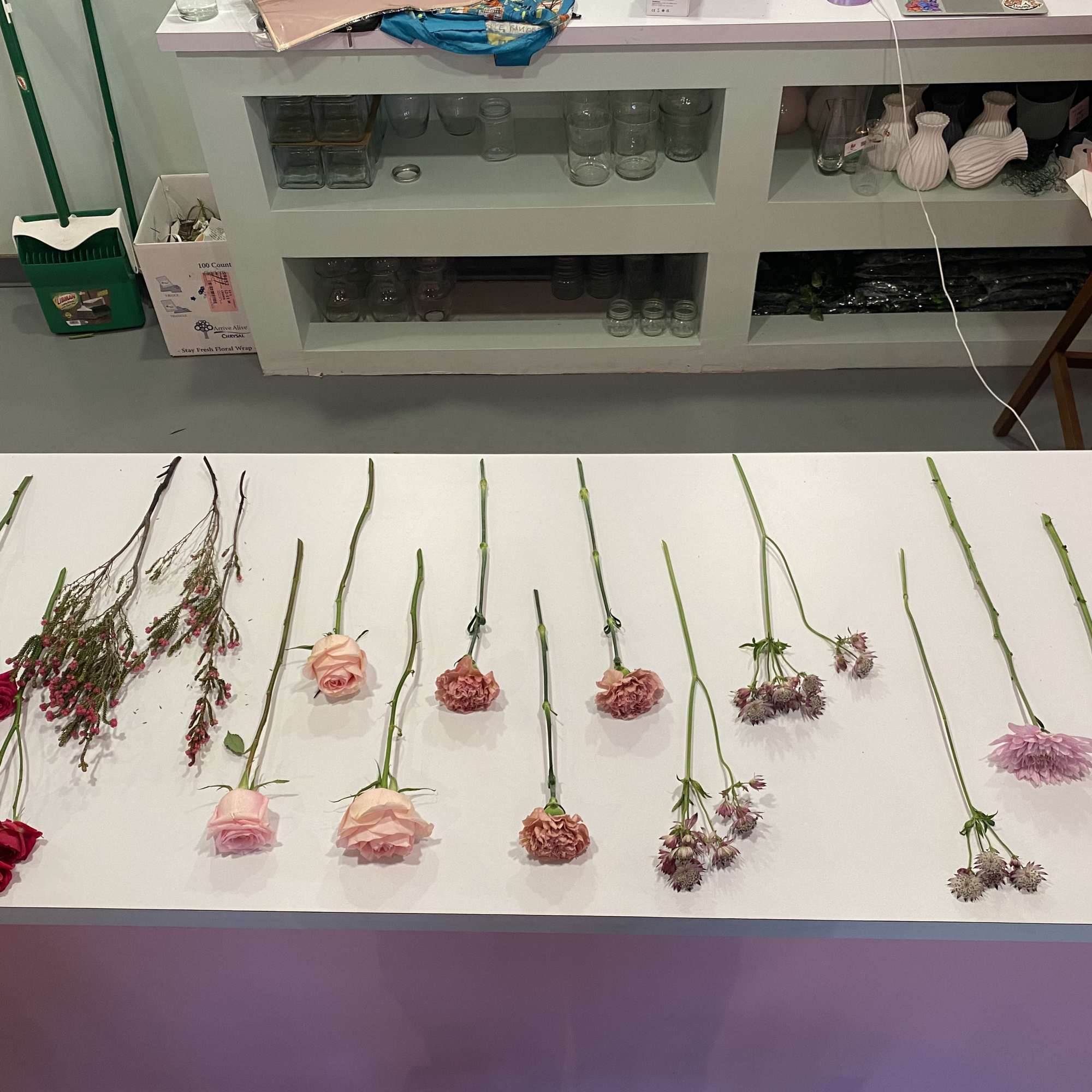 Assorted cut flowers laid out on a table, including roses and small pink blooms