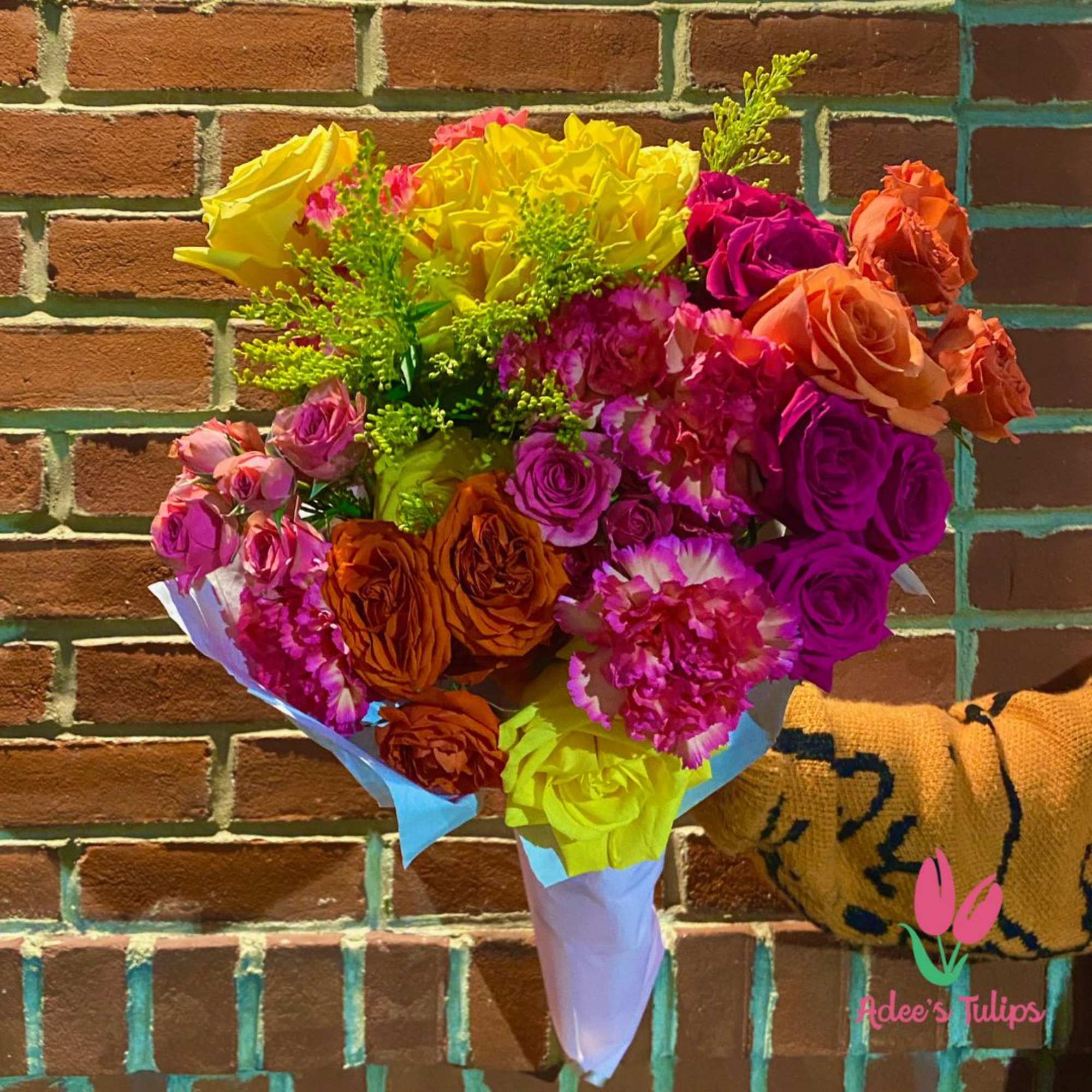 Bright mixed bouquet of roses and carnations wrapped in pastel paper
