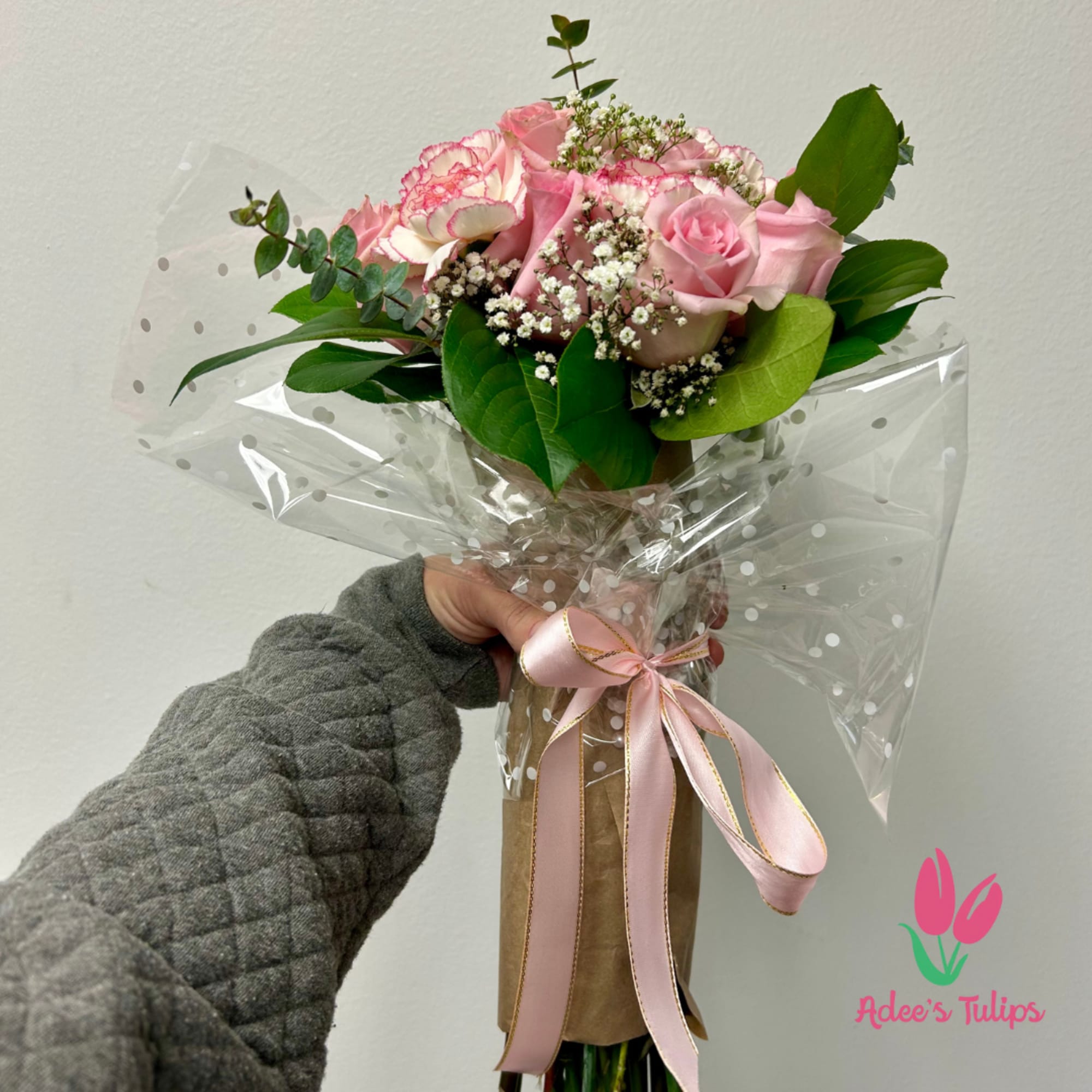 Pink rose bouquet with baby’s breath and greenery, wrapped in clear polka-dot plastic